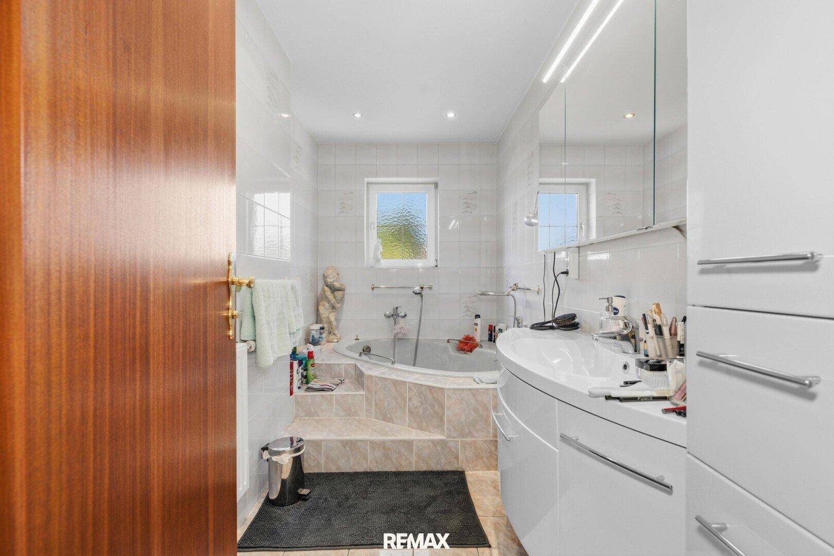 Geräumiges Badezimmer mit Eckbadewanne, modernem Waschtisch und Fenster.