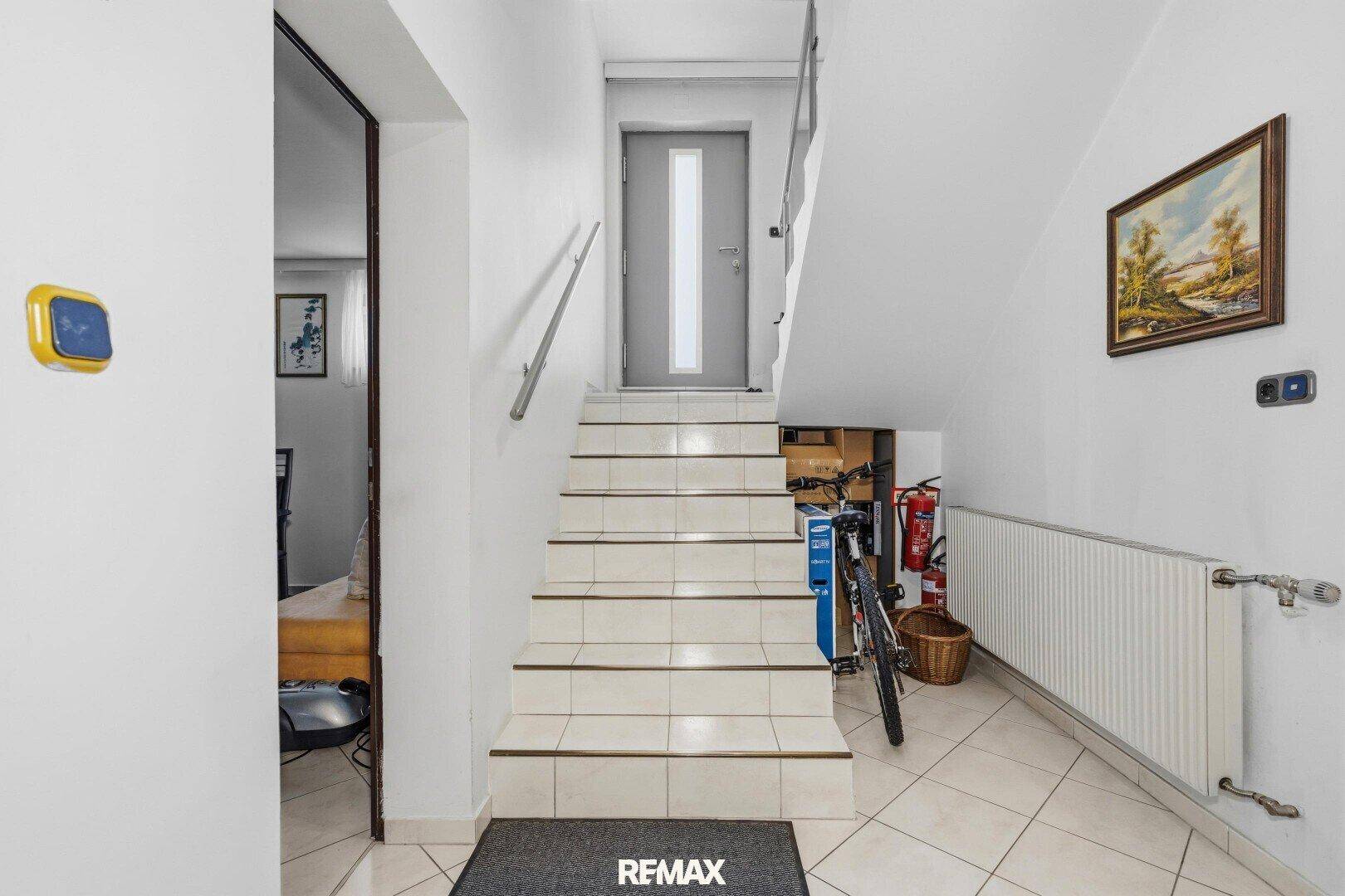 Eingangsbereich zum Keller mit gefliester Treppe und Fahrradabstellmöglichkeit.