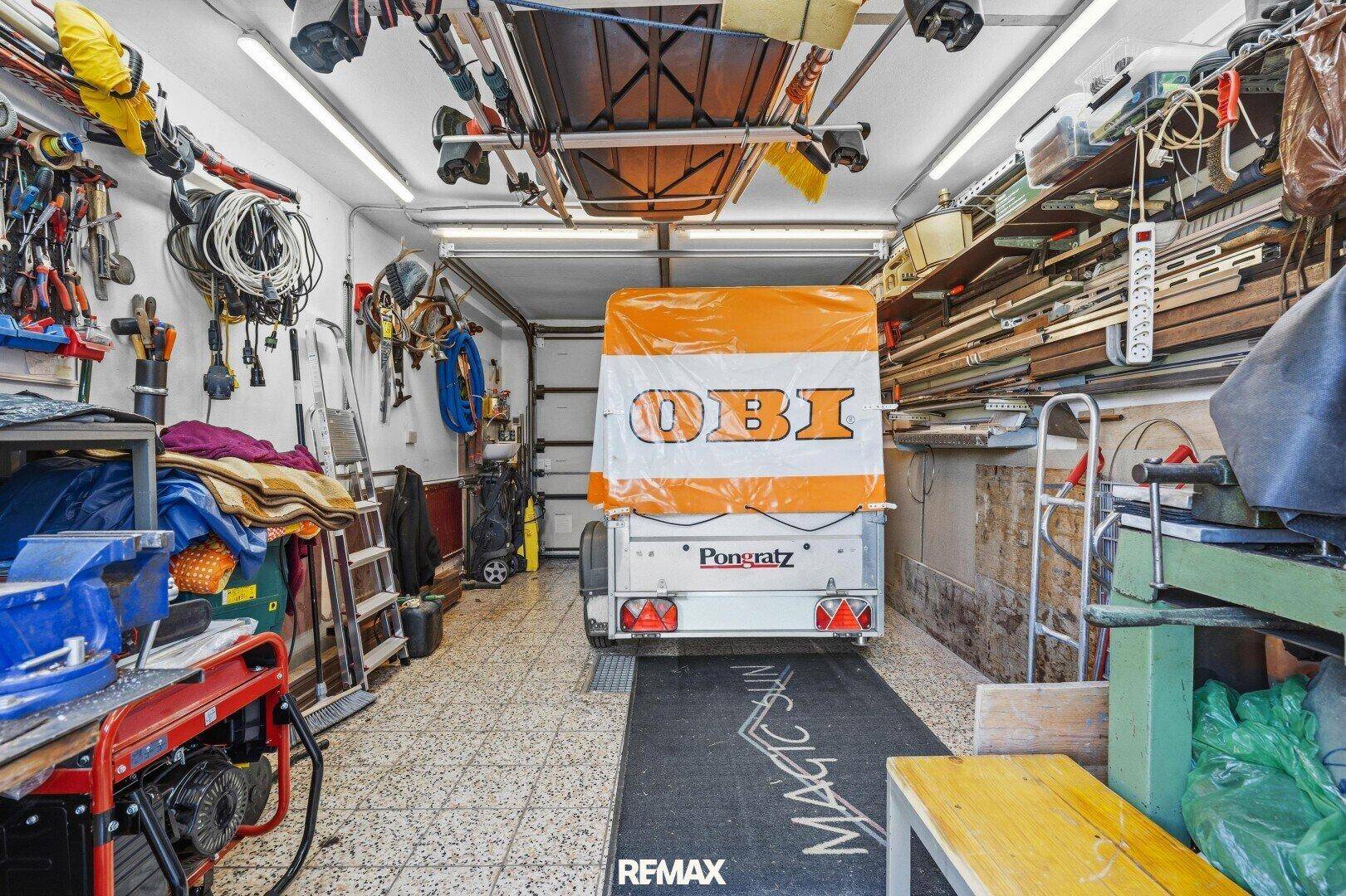 Gut ausgestattete Garage mit Werkzeugen, Regalen und einem Anhänger, ideal für Heimwerker.