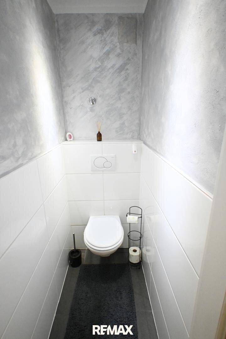 Separates WC mit Wand-WC und modernem Fliesen- und Wanddesign.