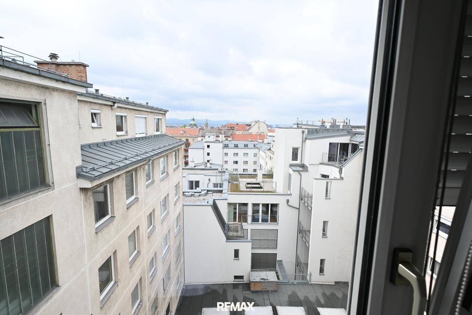 Blick aus dem Fenster auf die umliegenden Gebäude und Dächer der Stadt.