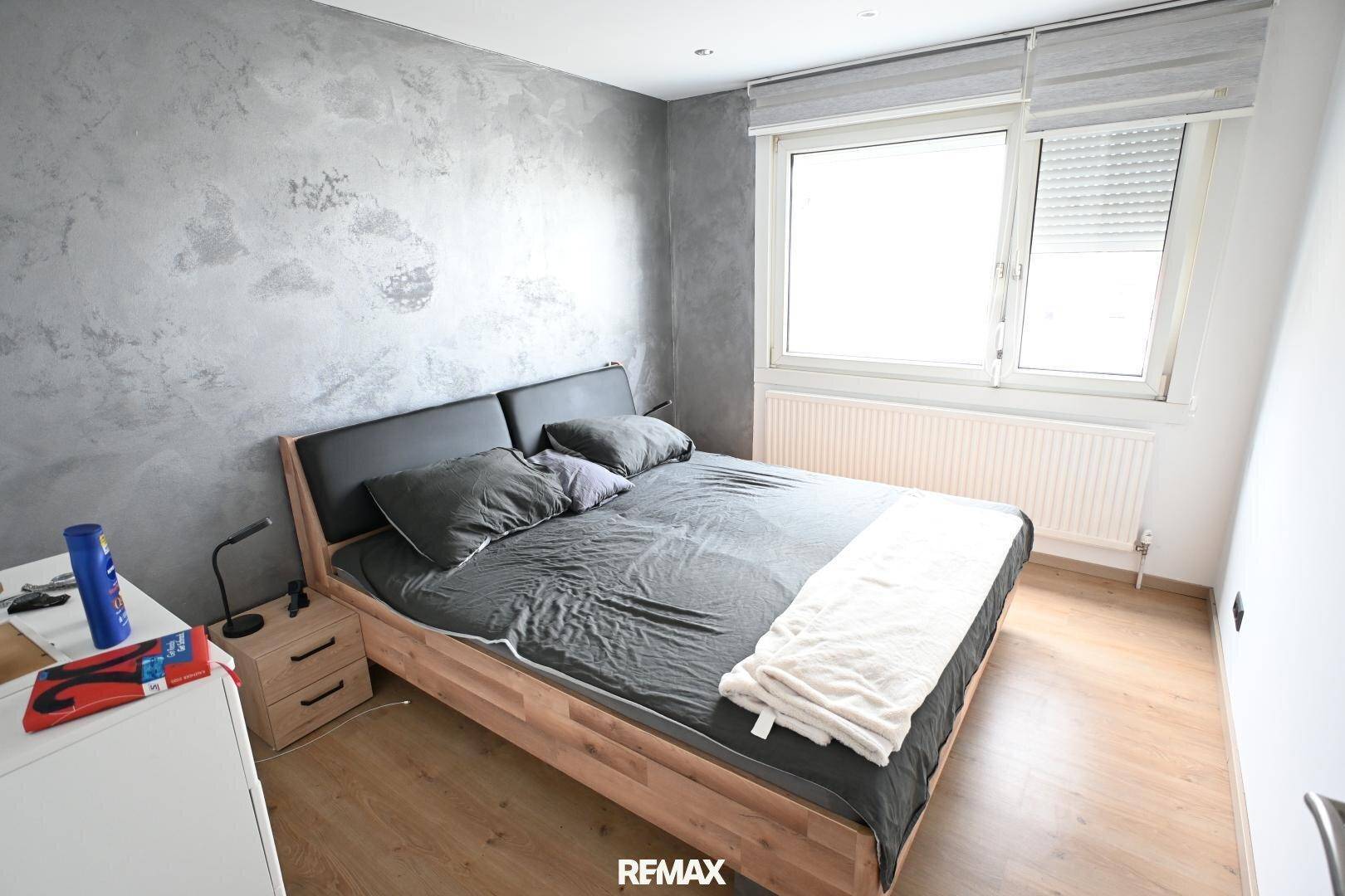 Schlafzimmer mit Doppelbett, modernem Wanddesign und großem Fenster für viel Licht.