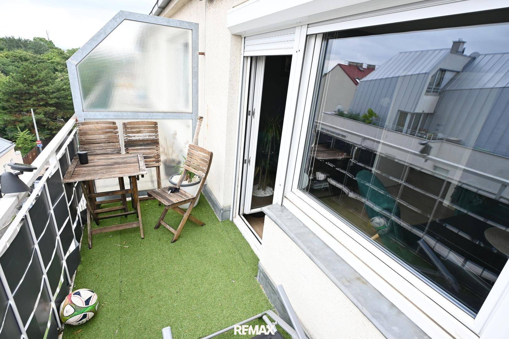 Gemütlicher Balkon mit Kunstrasen, Holztisch und Stühlen, ideal zum Entspannen.