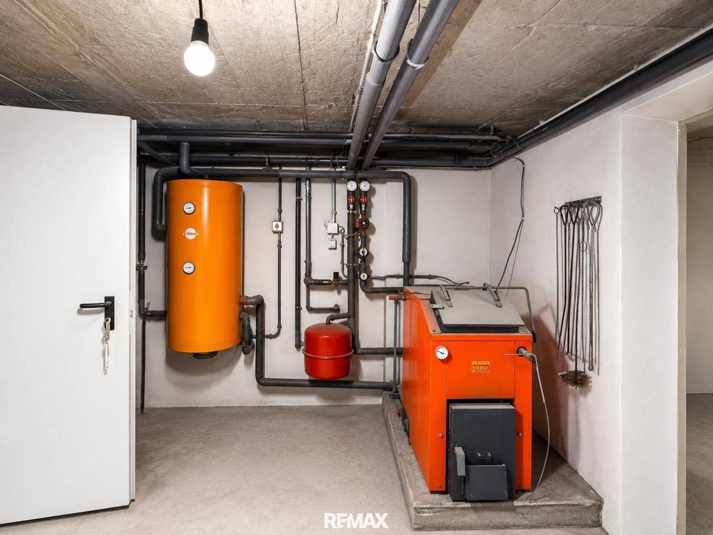 Heizraum im Keller mit älterer Heizungsanlage und Warmwasserspeicher in funktionsfähigem Zustand.
