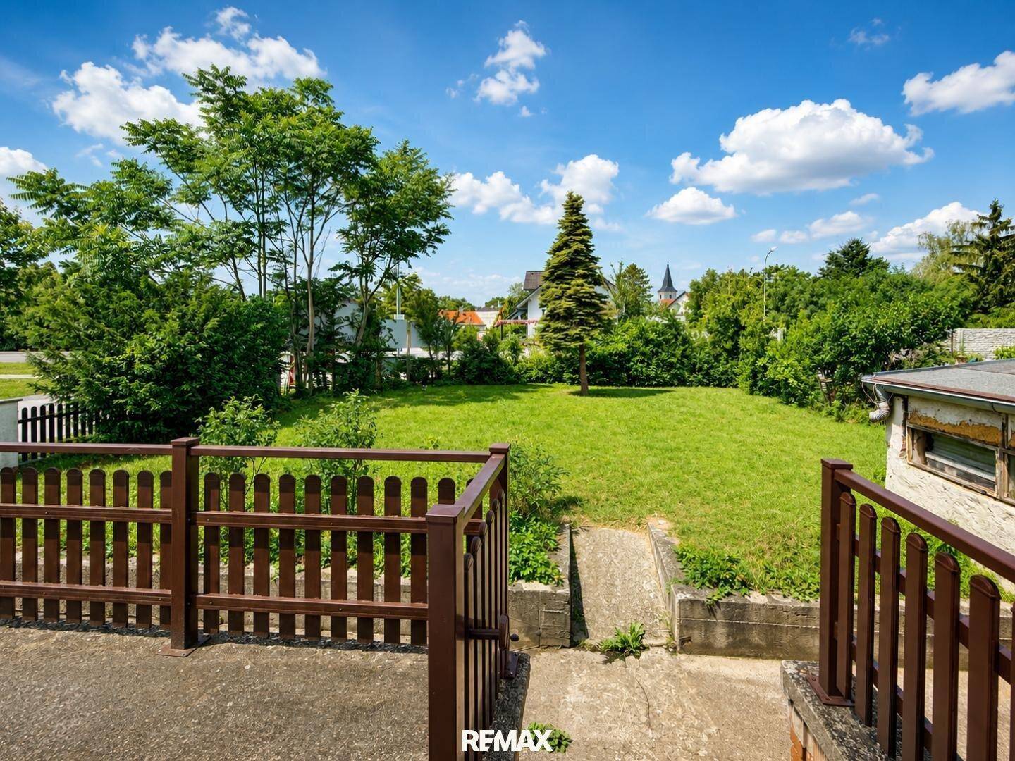 Weitläufiger Gartenbereich mit altem Baumbestand und Blick auf die umliegende Landschaft.