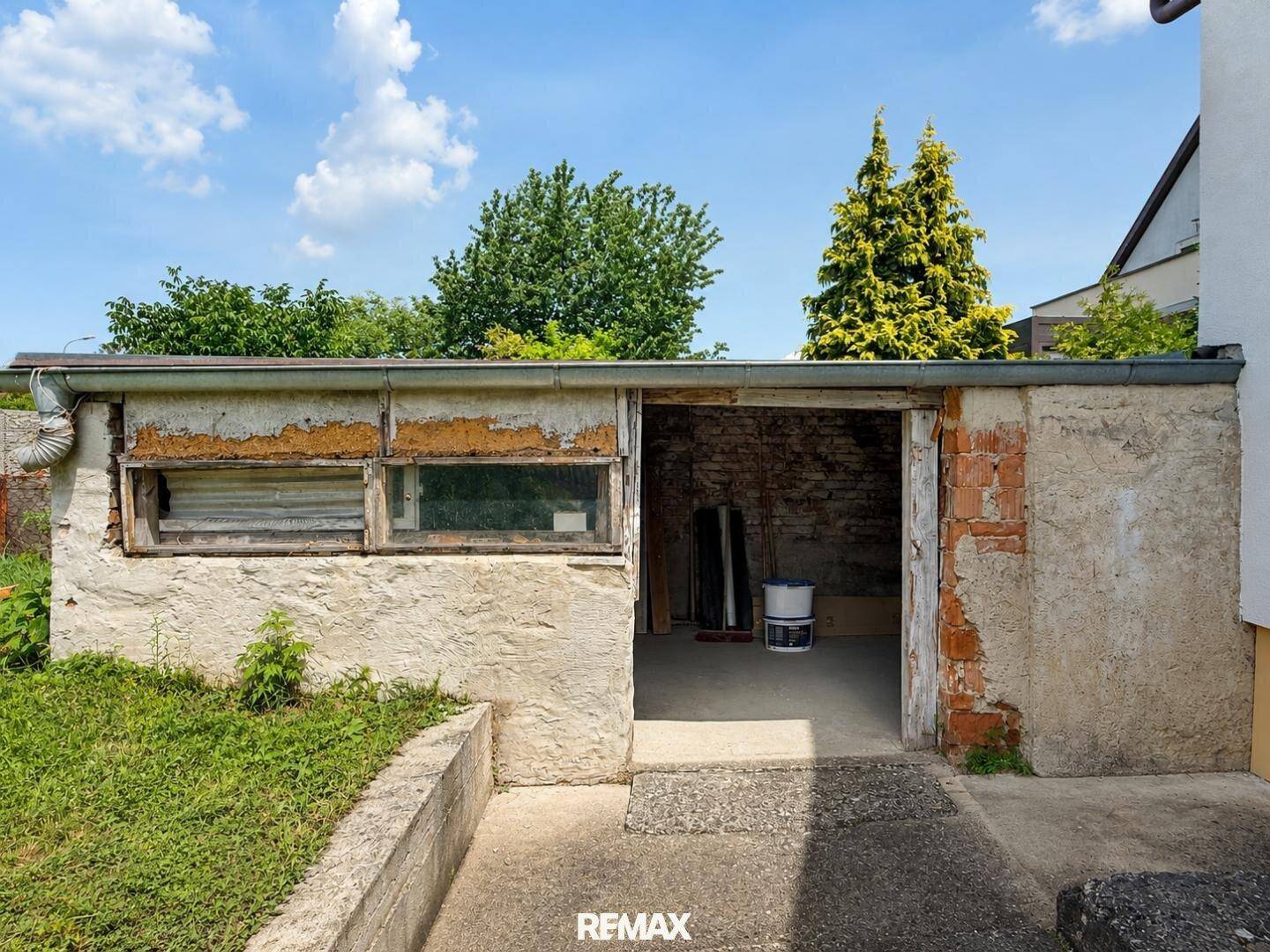 Ältere Garage oder Nebengebäude mit sichtbaren Gebrauchsspuren im Gartenbereich.