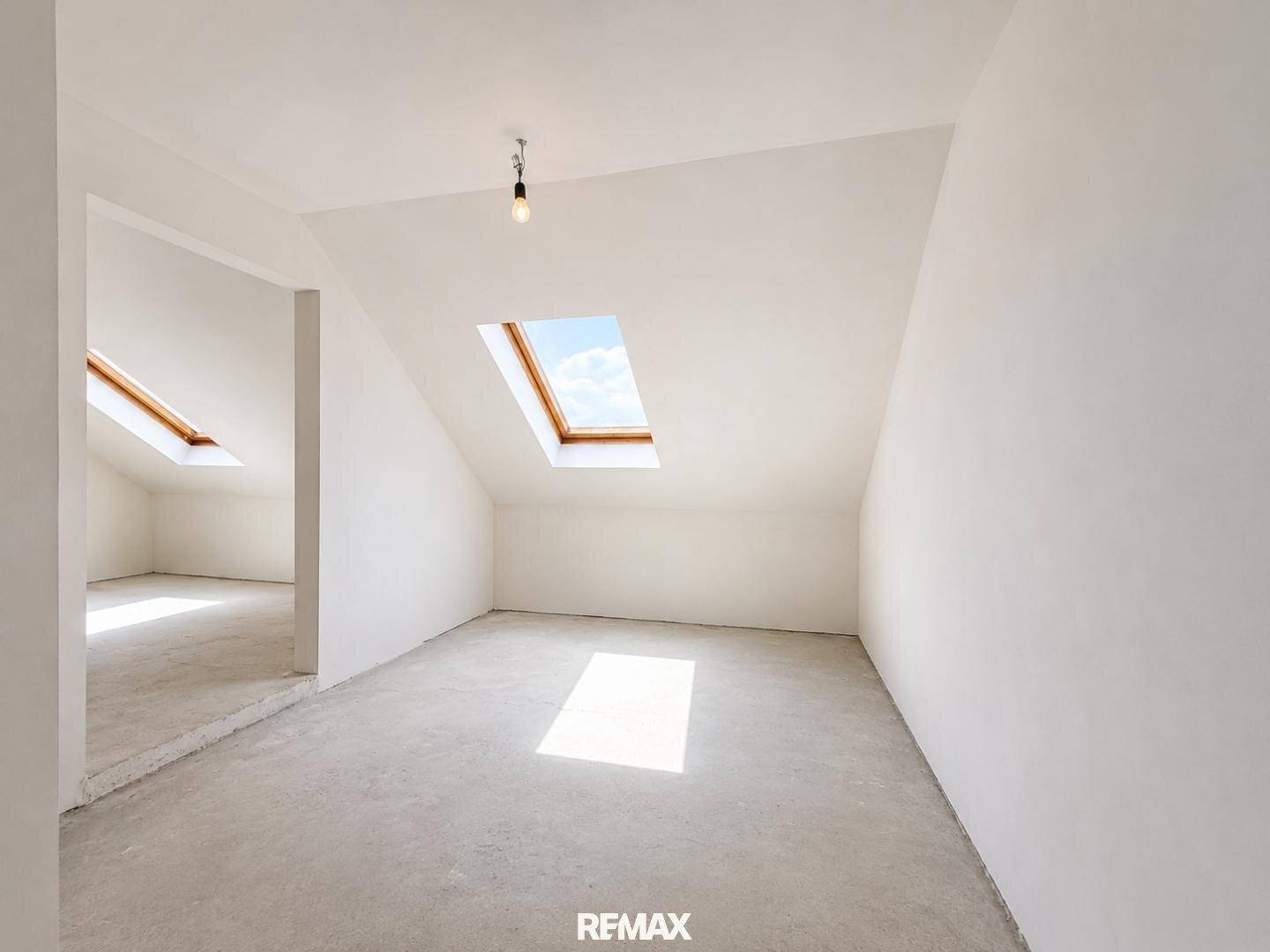 Helles Dachgeschosszimmer mit zwei Dachfenstern, die viel natürliches Licht hereinlassen.
