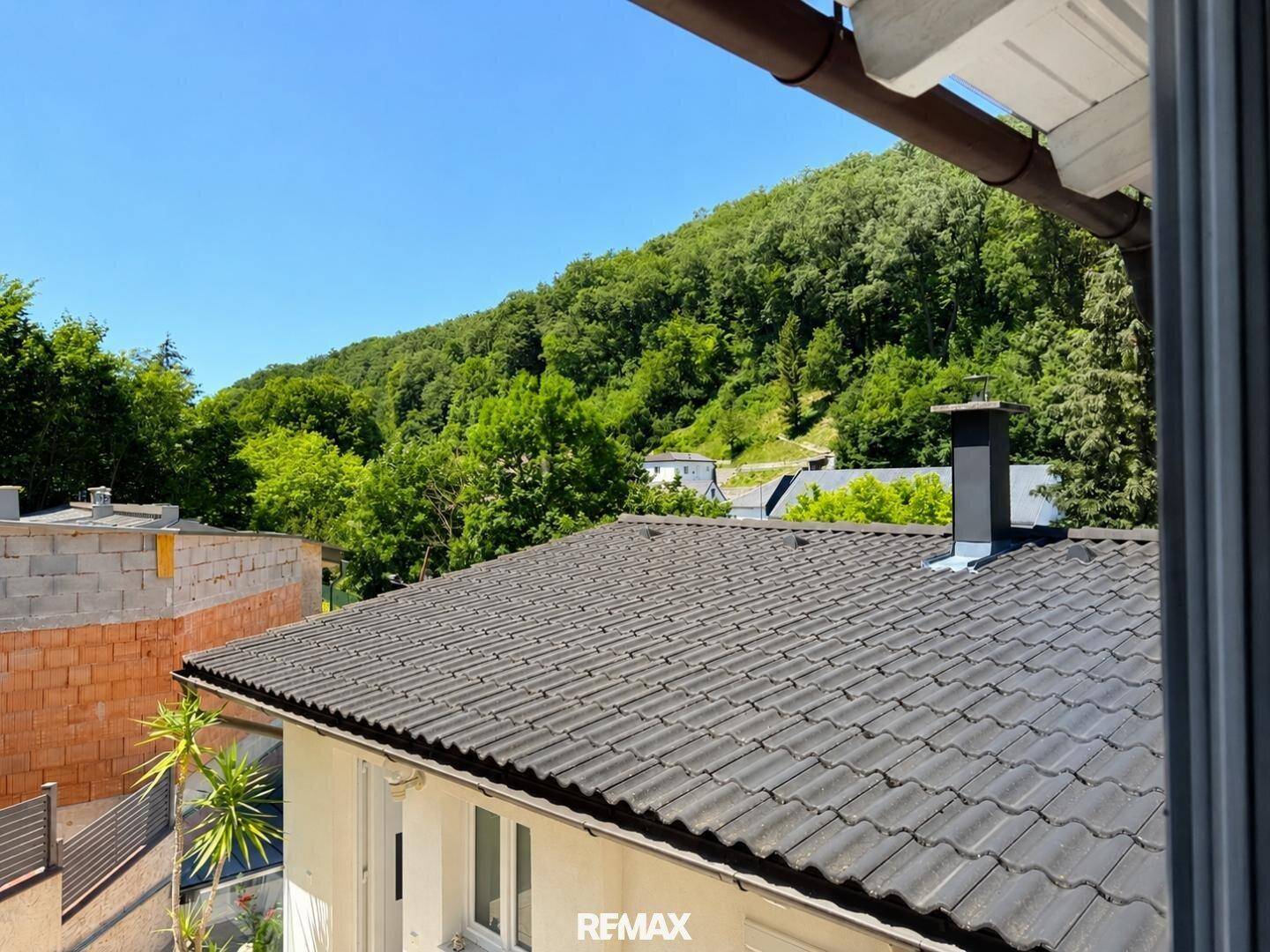 Blick auf das Dach des Hauses und die umliegende grüne Hügellandschaft.