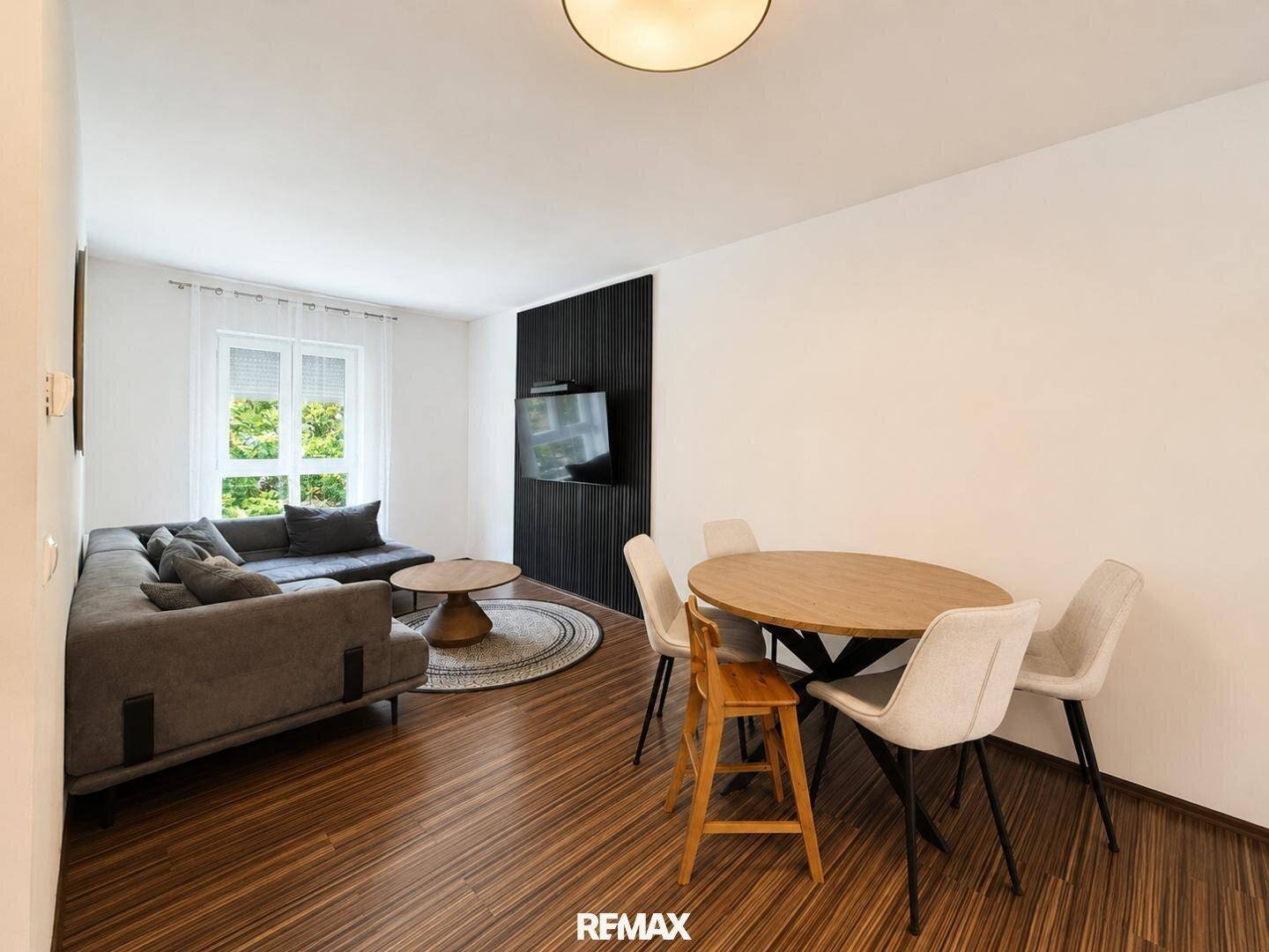 Heller Wohn- und Essbereich mit modernem Sofa, Esstisch und Holzboden.