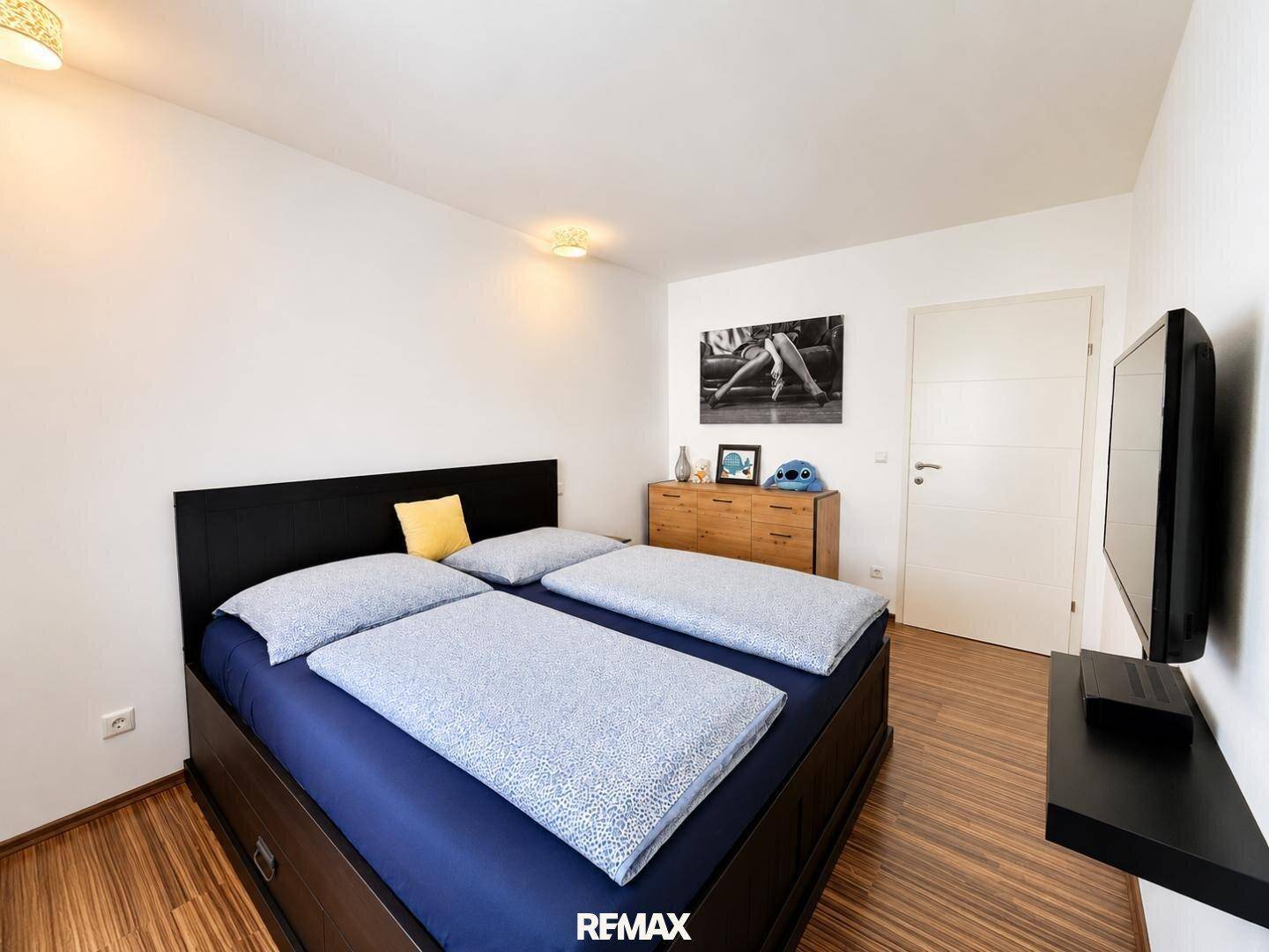 Gemütliches Schlafzimmer mit Doppelbett, Holzboden und moderner Wanddekoration.