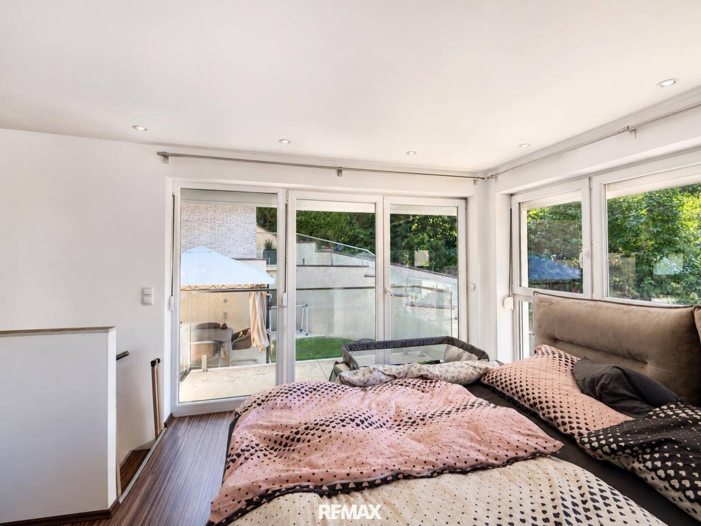 Schlafzimmer mit großen Fenstern und Blick auf den Garten oder die Terrasse.