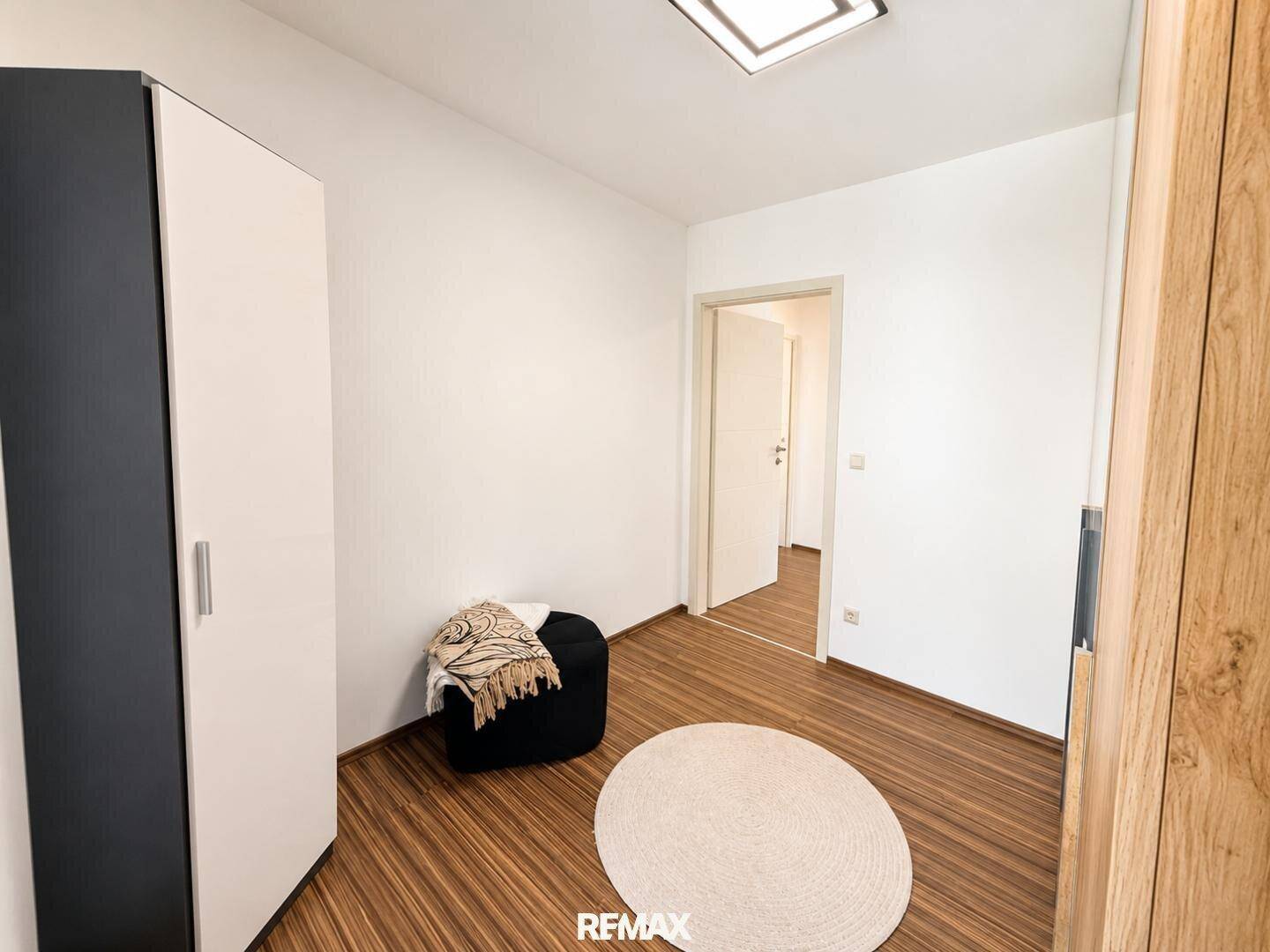Helles Schlafzimmer mit Holzboden und weißem Kleiderschrank, bereit zur individuellen Gestaltung.