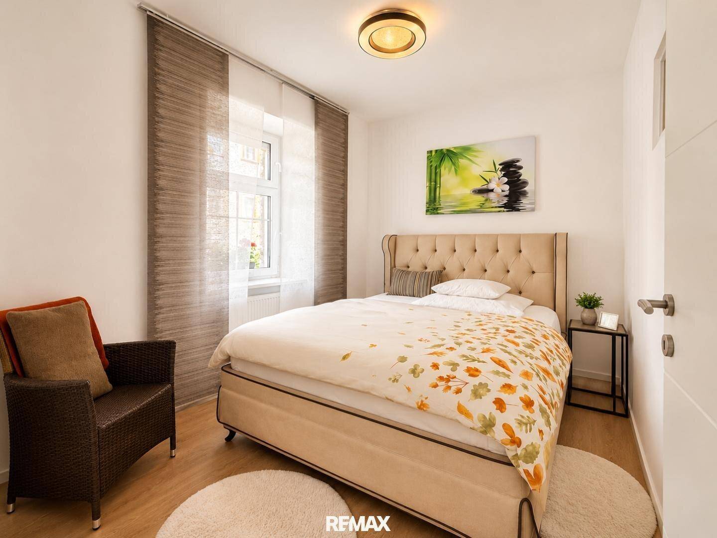 Helles Schlafzimmer mit gepolstertem Doppelbett, Holzboden und dekorativen Vorhängen.