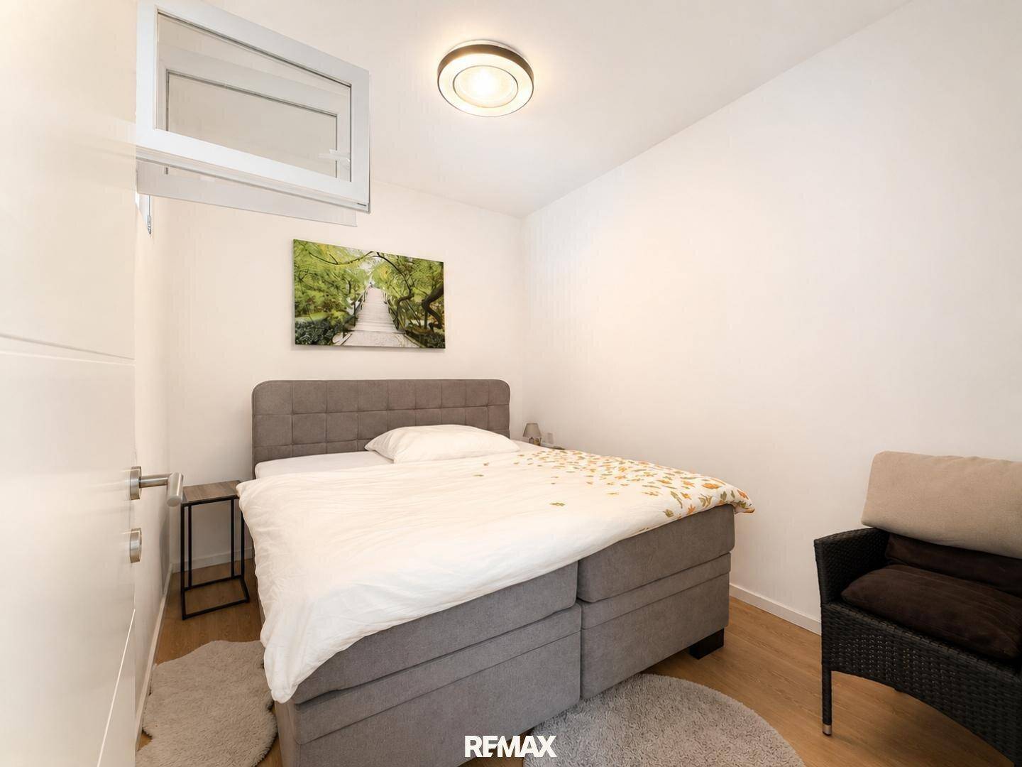 Gemütliches Schlafzimmer mit Doppelbett, Holzboden und einem kleinen Fenster.