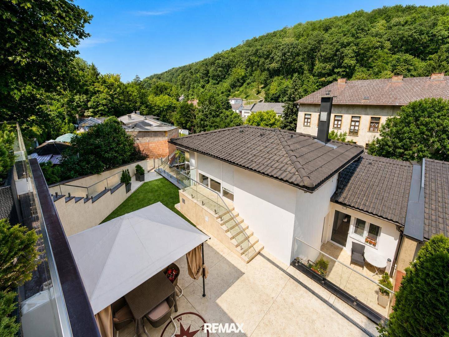 Überblick über die Terrassenbereiche und den Garten mit Pavillon und umliegender Natur.