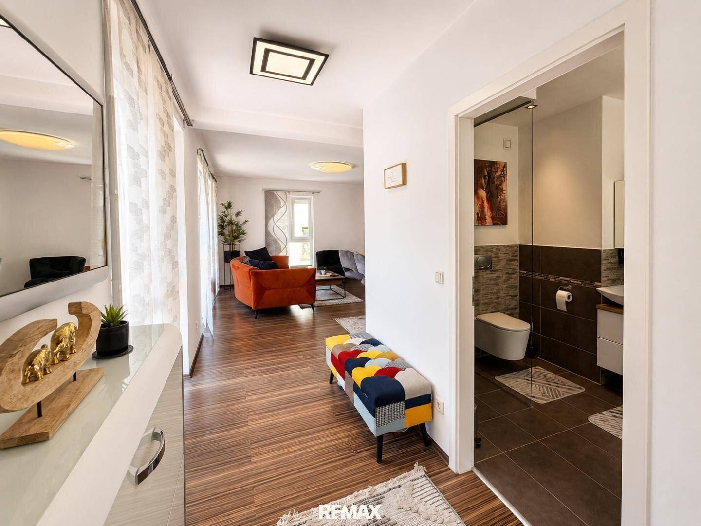 Geräumiger Flur mit Holzboden, farbenfroher Sitzbank und Zugang zum Wohnbereich und Bad.