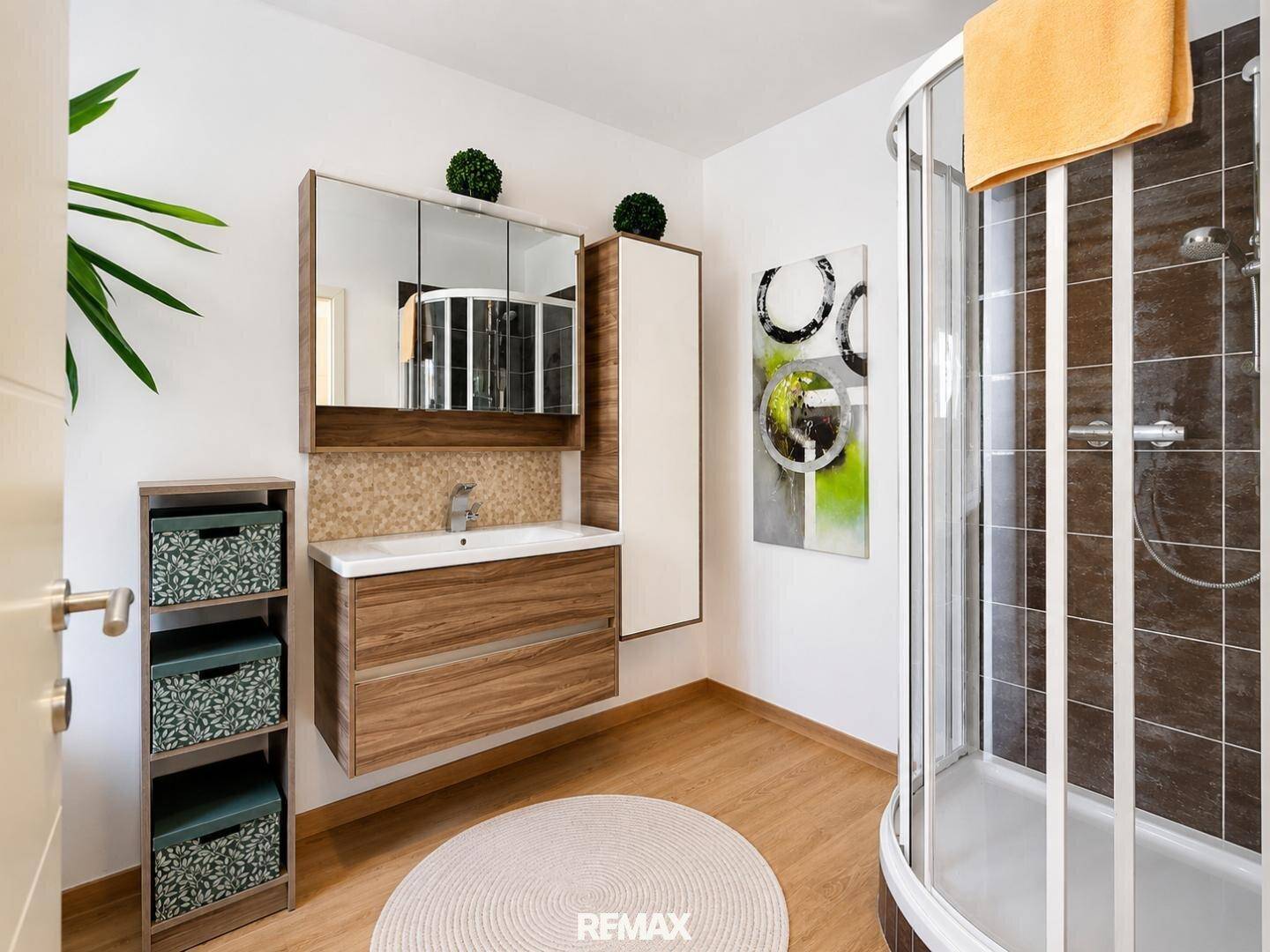 Modernes Badezimmer mit Duschkabine, Einzelwaschbecken und Spiegelschrank.