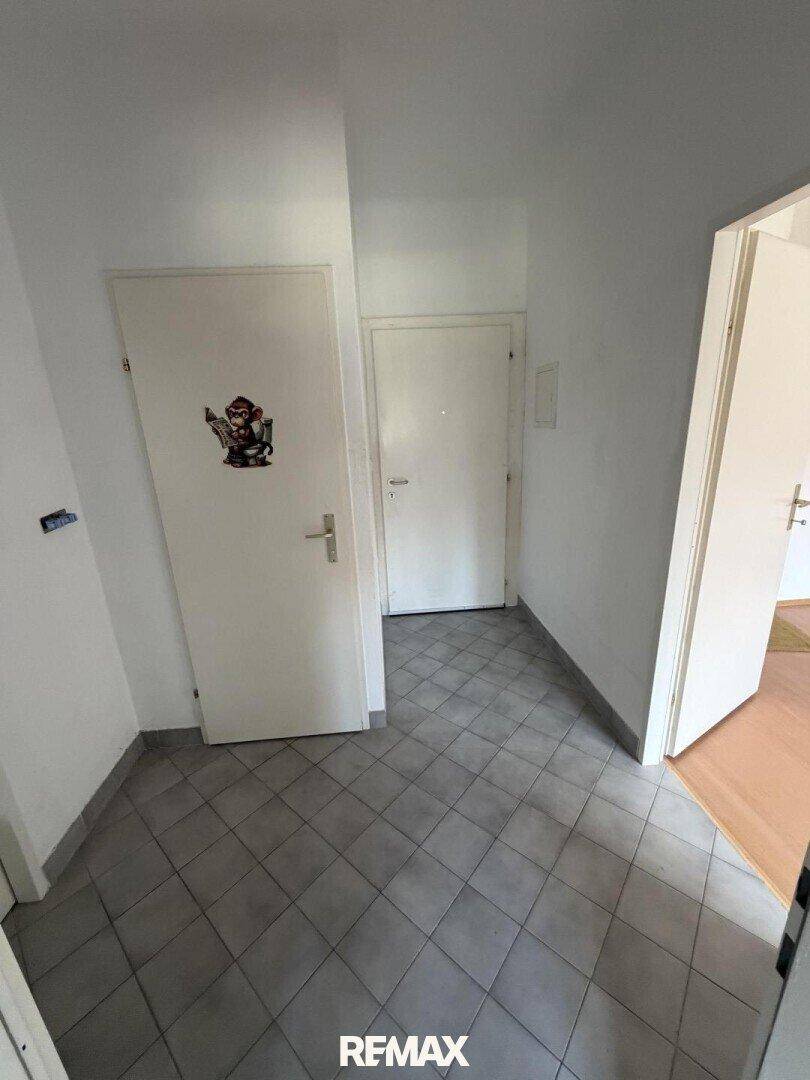 Heller Flur mit Fliesenboden und mehreren Türen, verbindet die Räume.