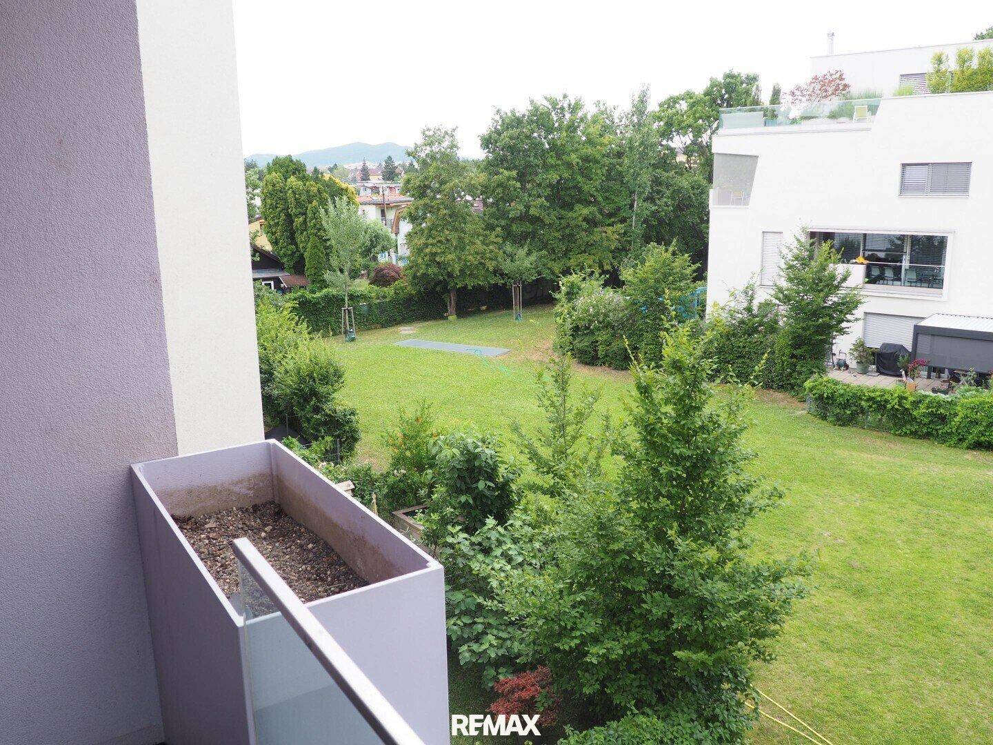 Balkon mit Blick auf eine grüne Gartenanlage und die umliegenden Wohngebäude.