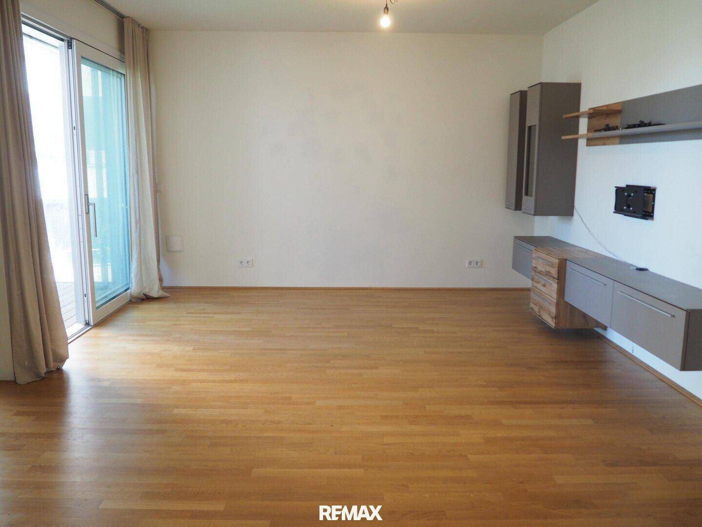 Helles Wohnzimmer mit Parkettboden, großen Schiebetüren und moderner Wanddekoration.