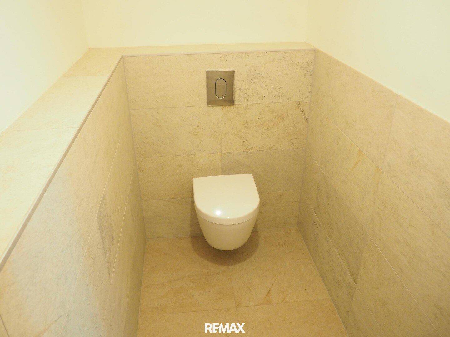 Separate Toilette mit wandhängendem WC und hellen, modernen Fliesen.