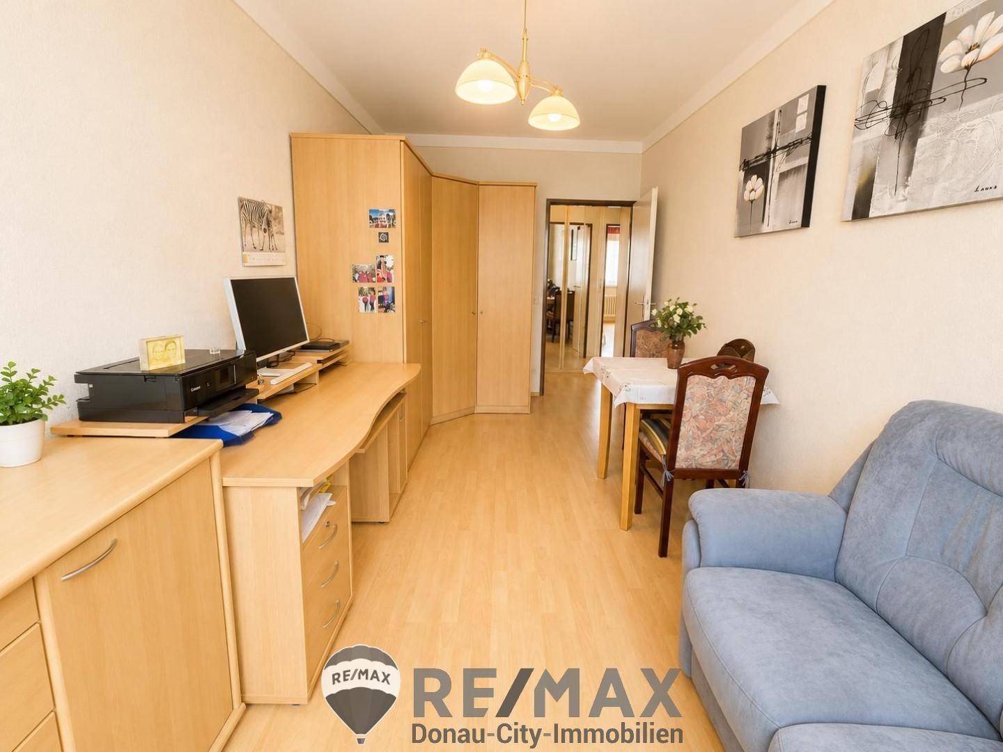 Heller Arbeitsbereich mit Schreibtisch, Stauraum und Blick in den Flur, ausgestattet mit Holzmöbeln.