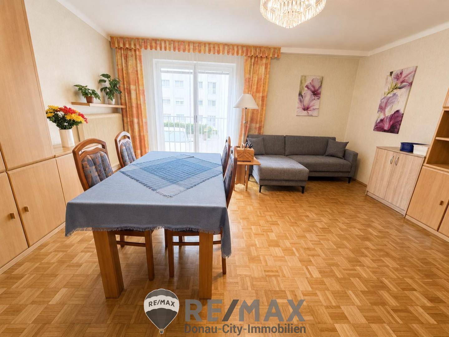Heller Wohn-Essbereich mit Parkettboden, gemütlichem Sofa und Zugang zum Balkon.