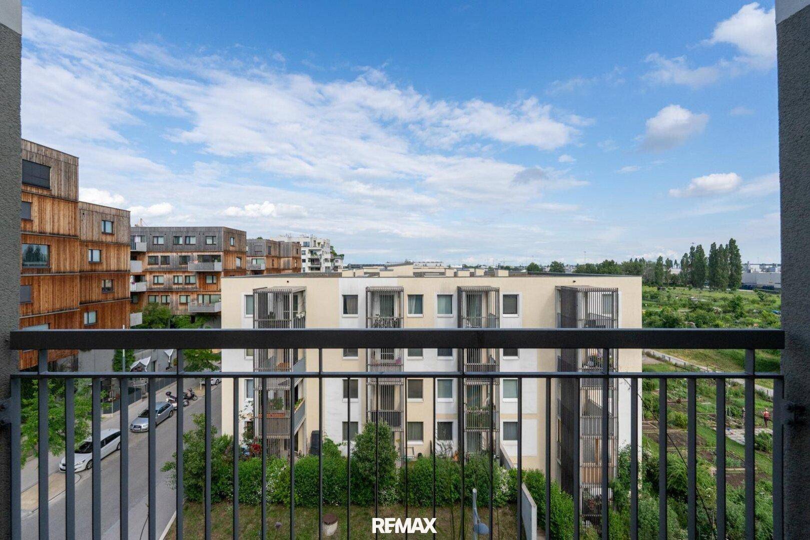 Weitblick von einem Balkon über eine Wohnsiedlung mit modernen Gebäuden und Straße.