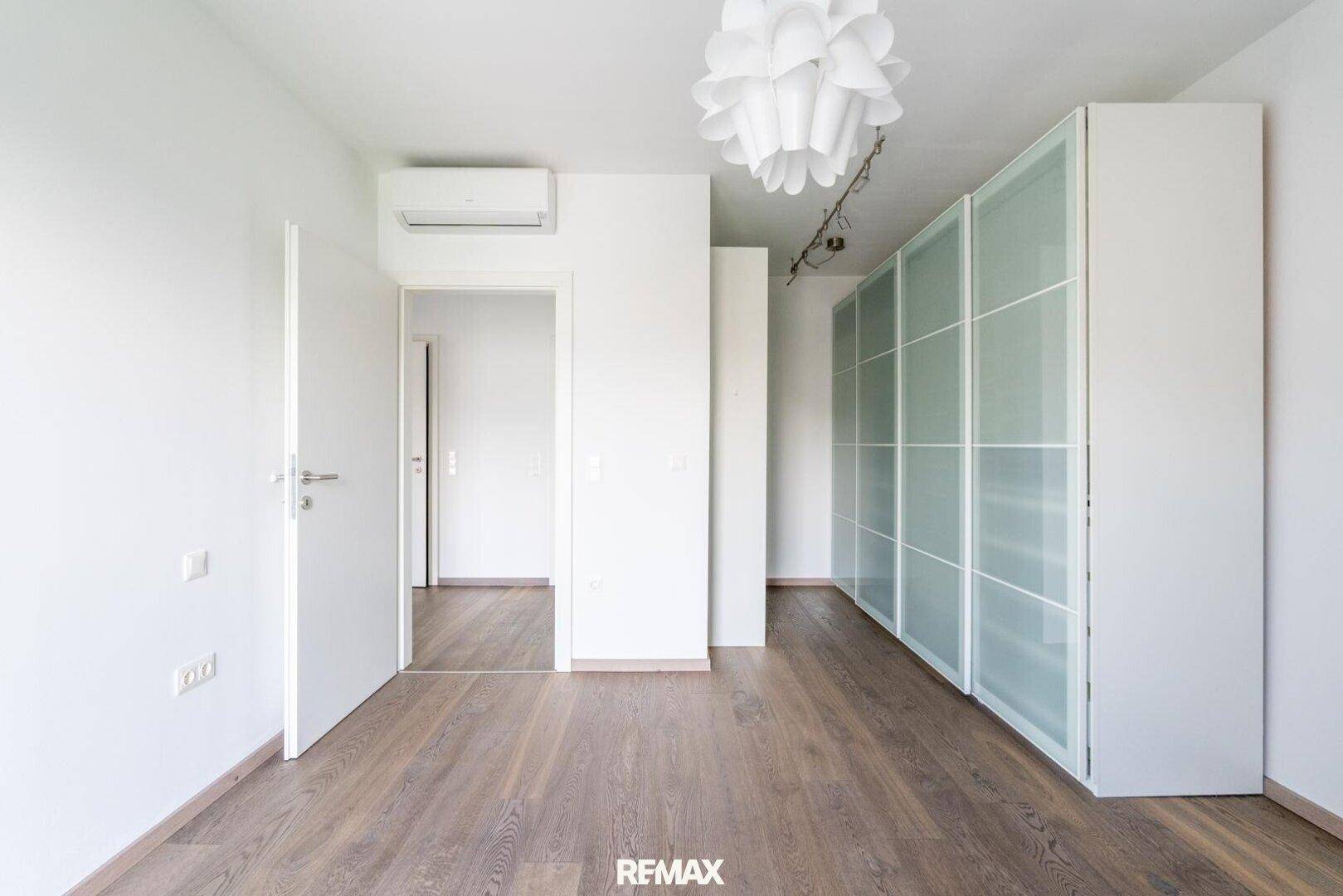 Schlafzimmer mit Holzboden, Einbauschrank und Klimaanlage, bereit zur individuellen Gestaltung.
