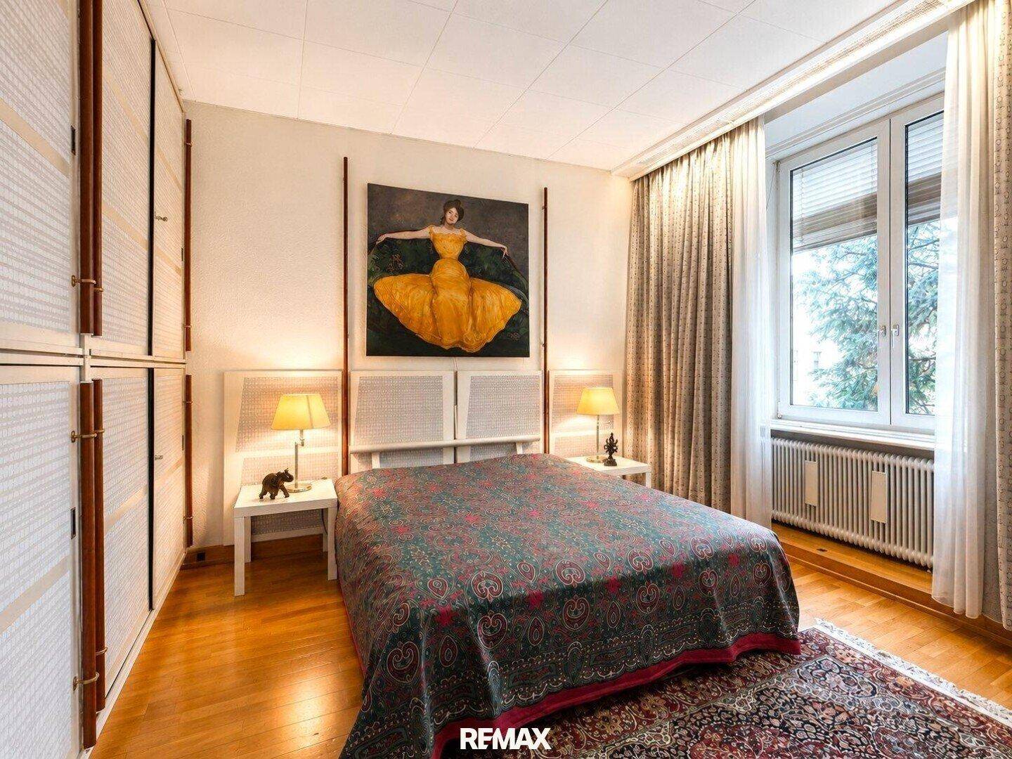 Helles Schlafzimmer mit Doppelbett, Holzboden, Einbauschränken und großem Fenster.