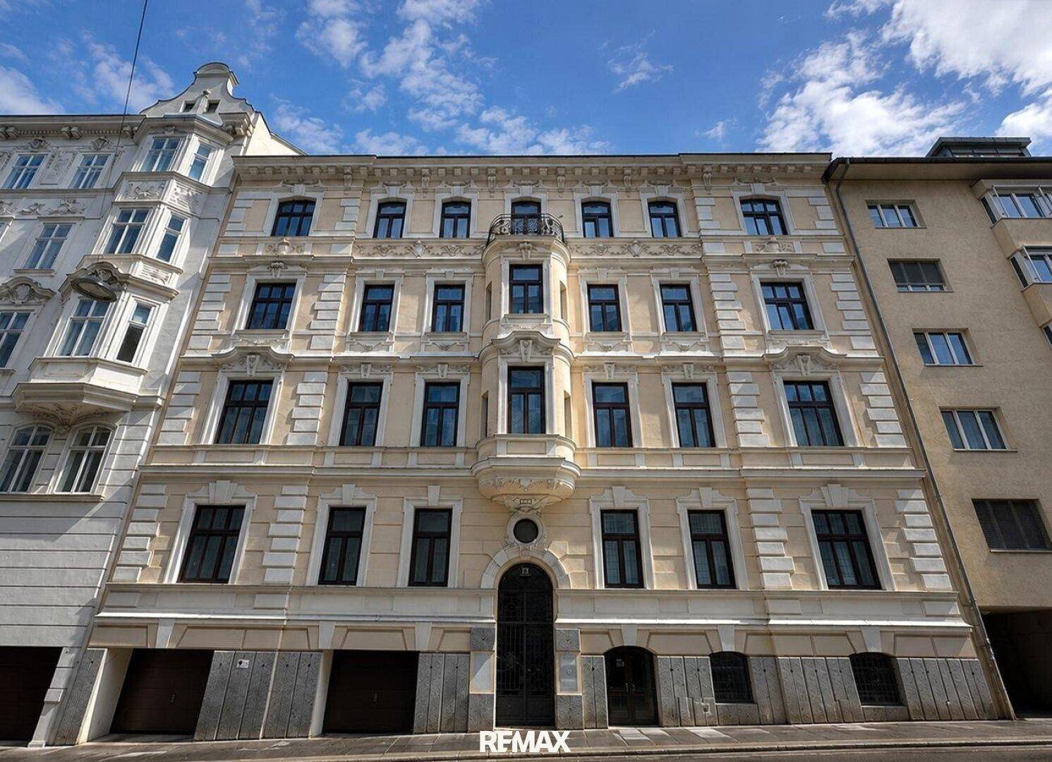 Klassische Fassade eines Altbaus mit vielen Fenstern und dekorativen Elementen.