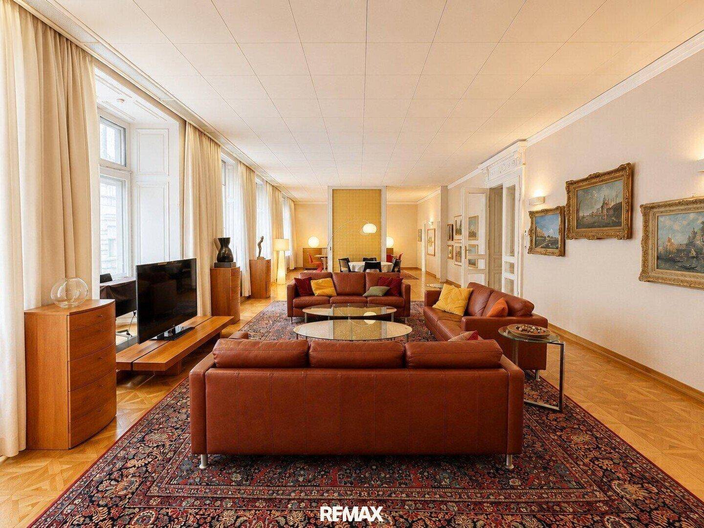 Großzügiges Wohnzimmer mit mehreren Ledersofas, Holzboden und traditionellen Teppichen.