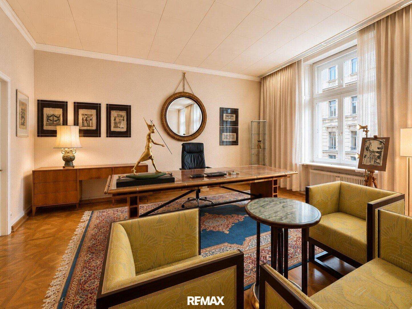 Elegantes Arbeitszimmer mit großem Schreibtisch, Holzboden und dekorativen Elementen.