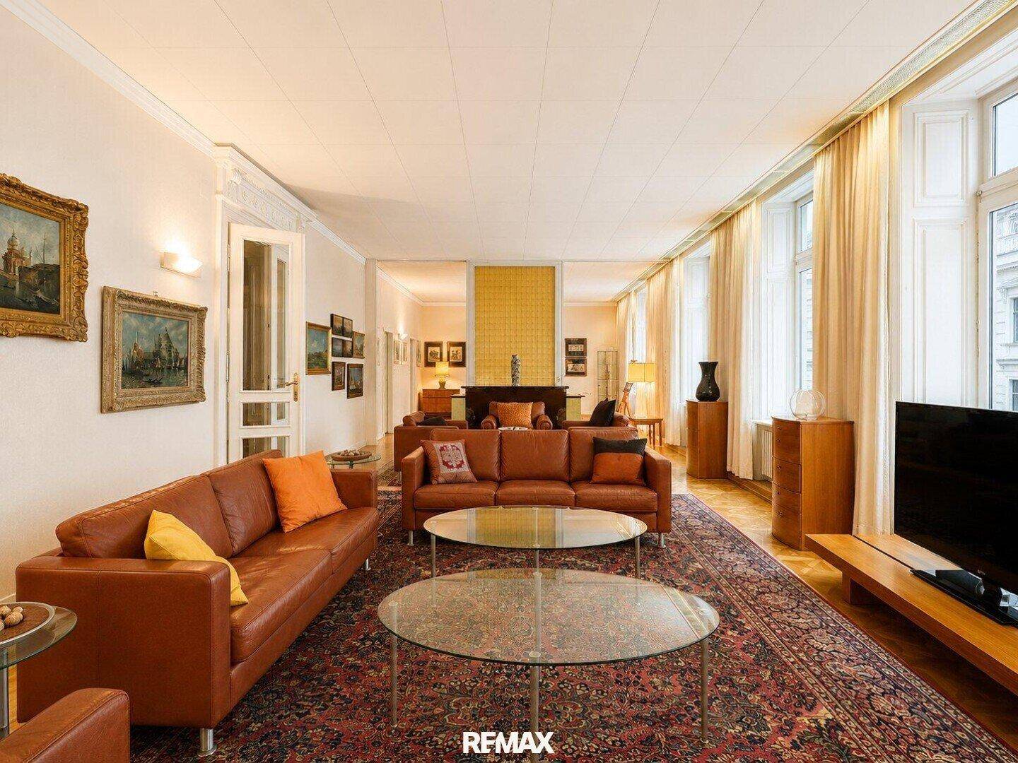 Weitläufiges Wohnzimmer mit bequemen Ledersofas, Holzboden und großen Fenstern.