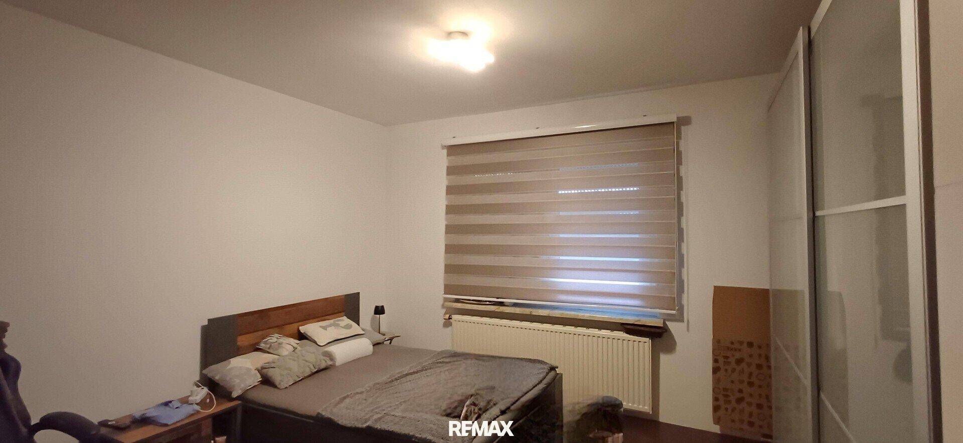 Schlafzimmer mit Doppelbett, Heizung unter dem Fenster und großem Kleiderschrank. Komfortabler Rückzugsort.