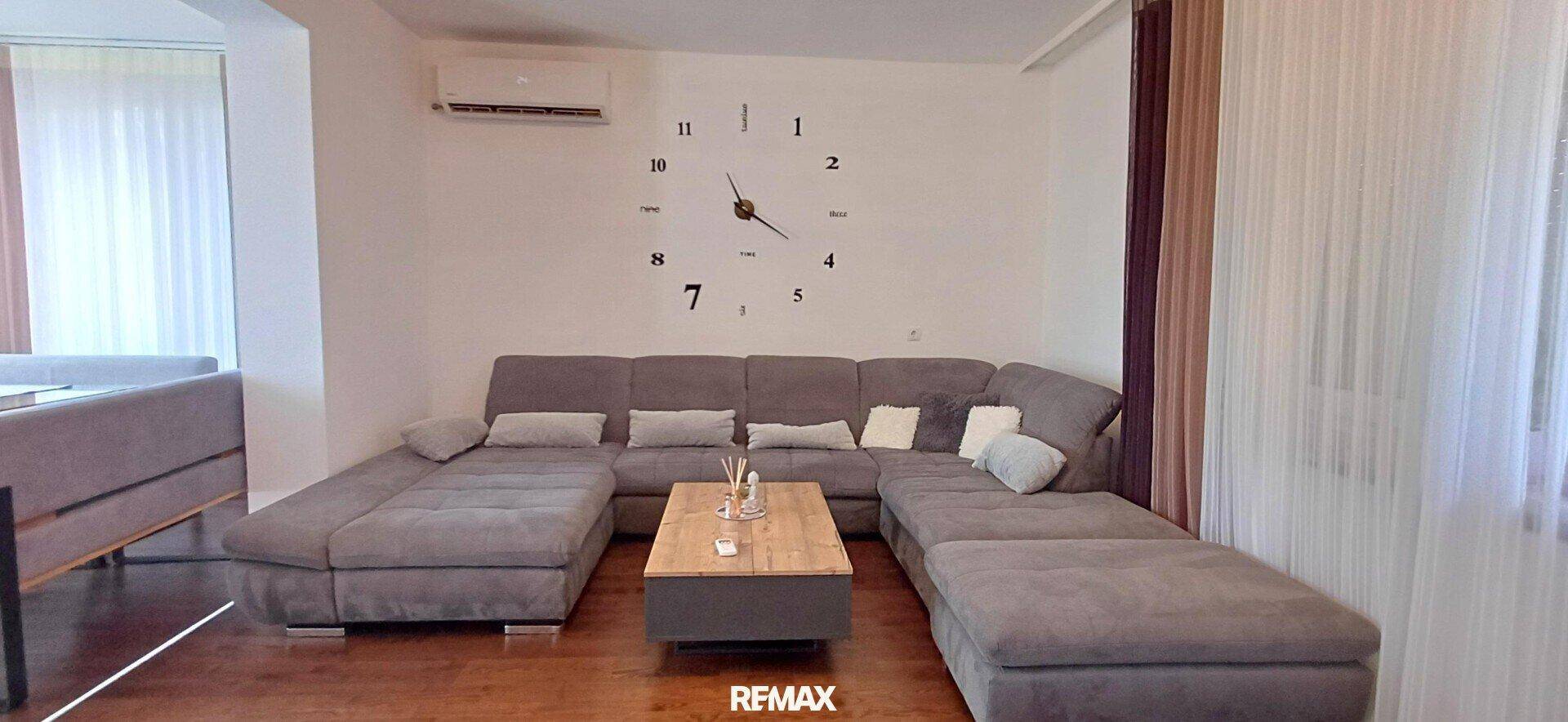Geräumiges Wohnzimmer mit großem Ecksofa, Holzboden und Klimaanlage für angenehmes Raumklima.