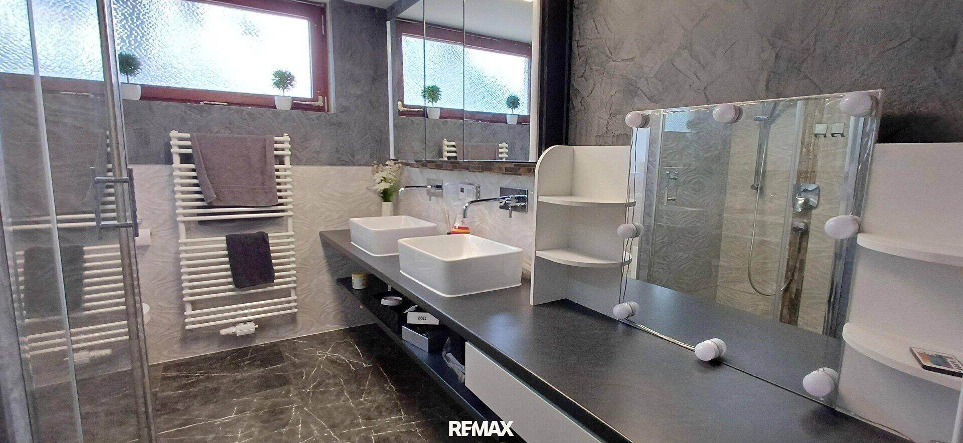 Modernes Badezimmer mit Doppelwaschbecken, großer begehbarer Dusche und Fenster. Stilvolle Einrichtung.