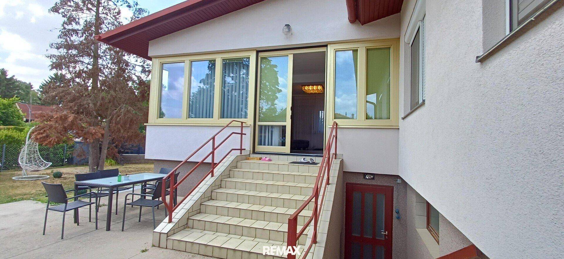 Hausfassade mit Außentreppe, Terrasse und Zugang zum Wintergarten. Einladender Eingangsbereich.