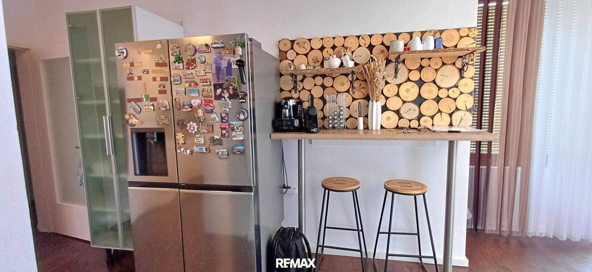 Küchenbereich mit großem Kühlschrank, praktischer Frühstücksbar und rustikaler Holzdekoration. Gemütliche Atmosphäre.