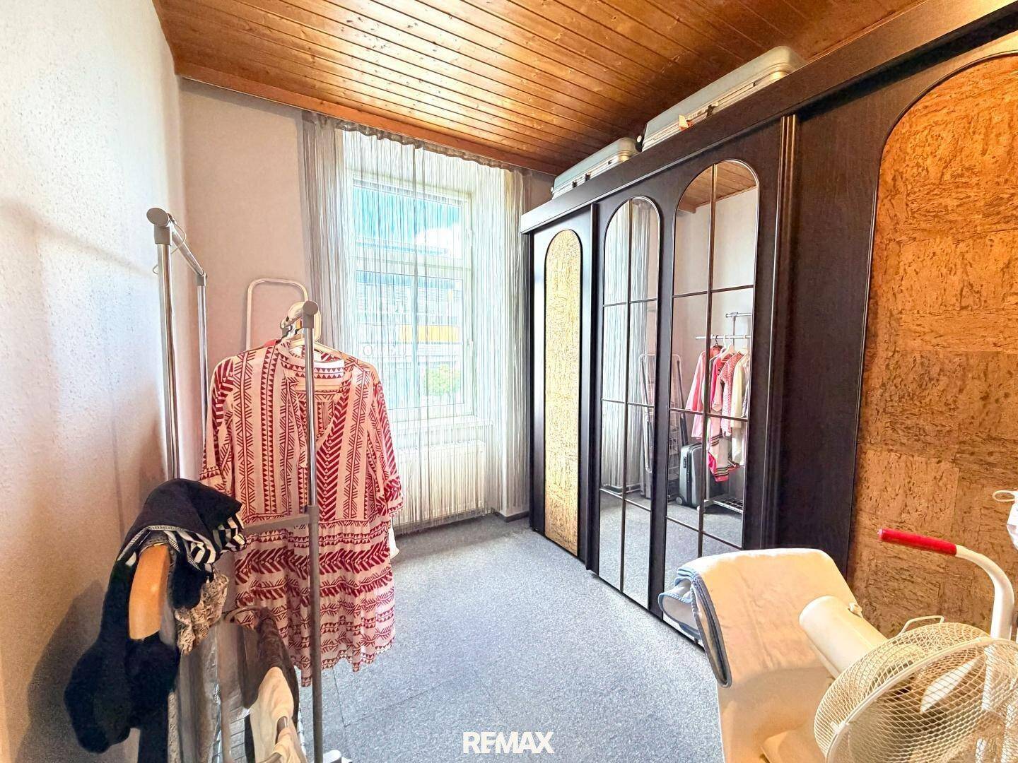 Schlafzimmer mit großem Spiegelschrank, Kleiderstange und Fenster für natürliche Belichtung.