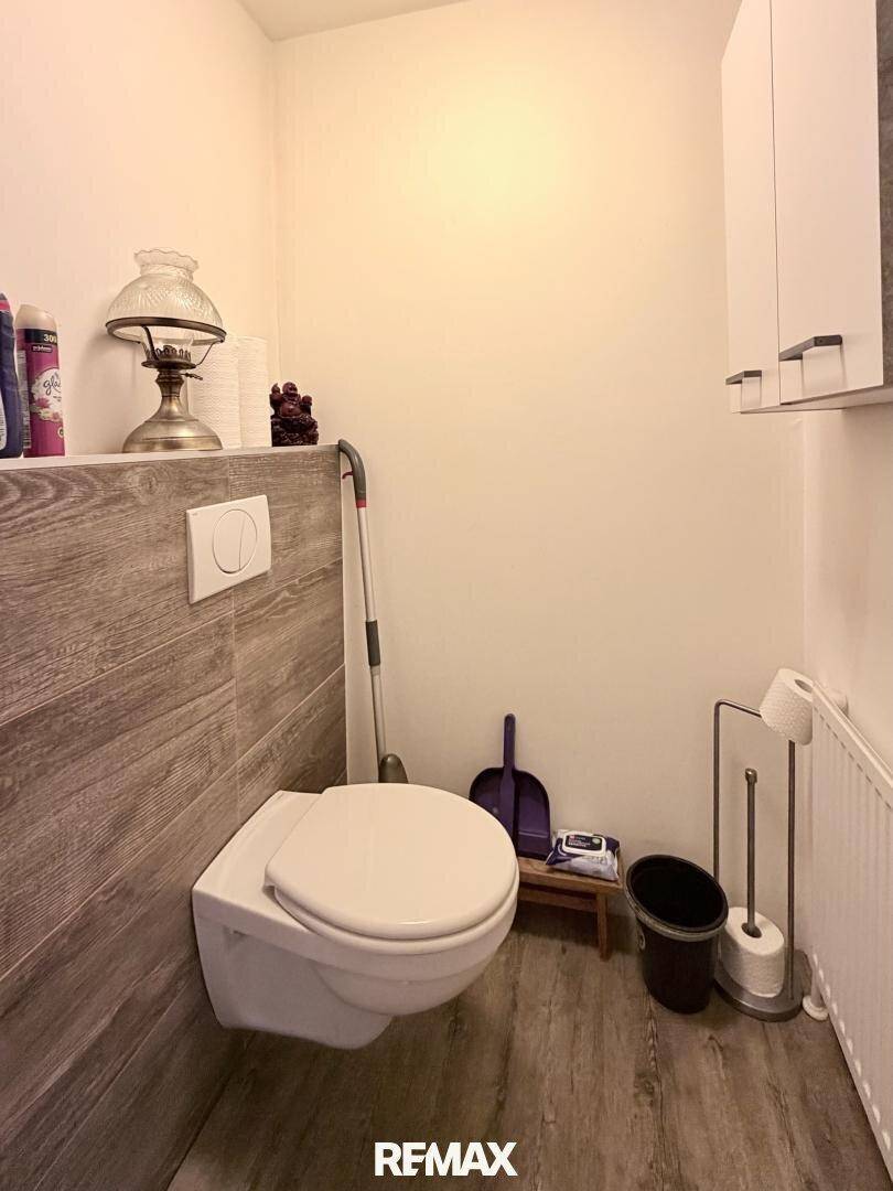 Separates WC mit wandhängender Toilette und modernen Holzoptik-Fliesen an der Wand.