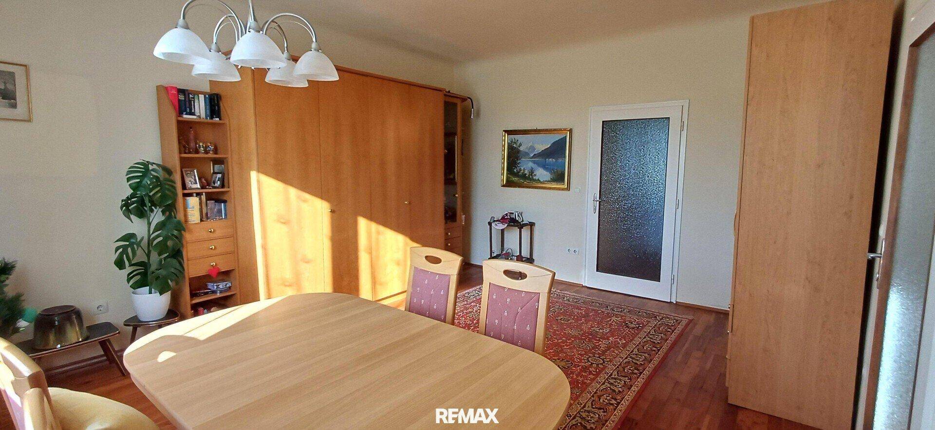 Geräumiger Essbereich mit großem Holzschrank, Esstisch und Zugang zu einem weiteren Raum.