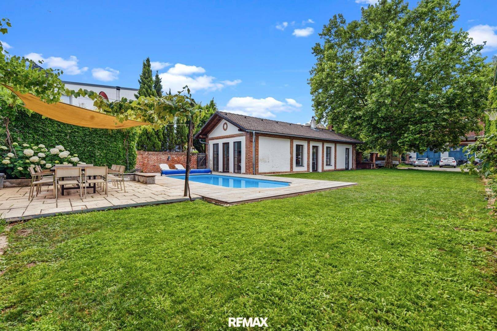Großer Garten mit Pool, Rasenfläche und Terrasse für entspannte Stunden im Freien.