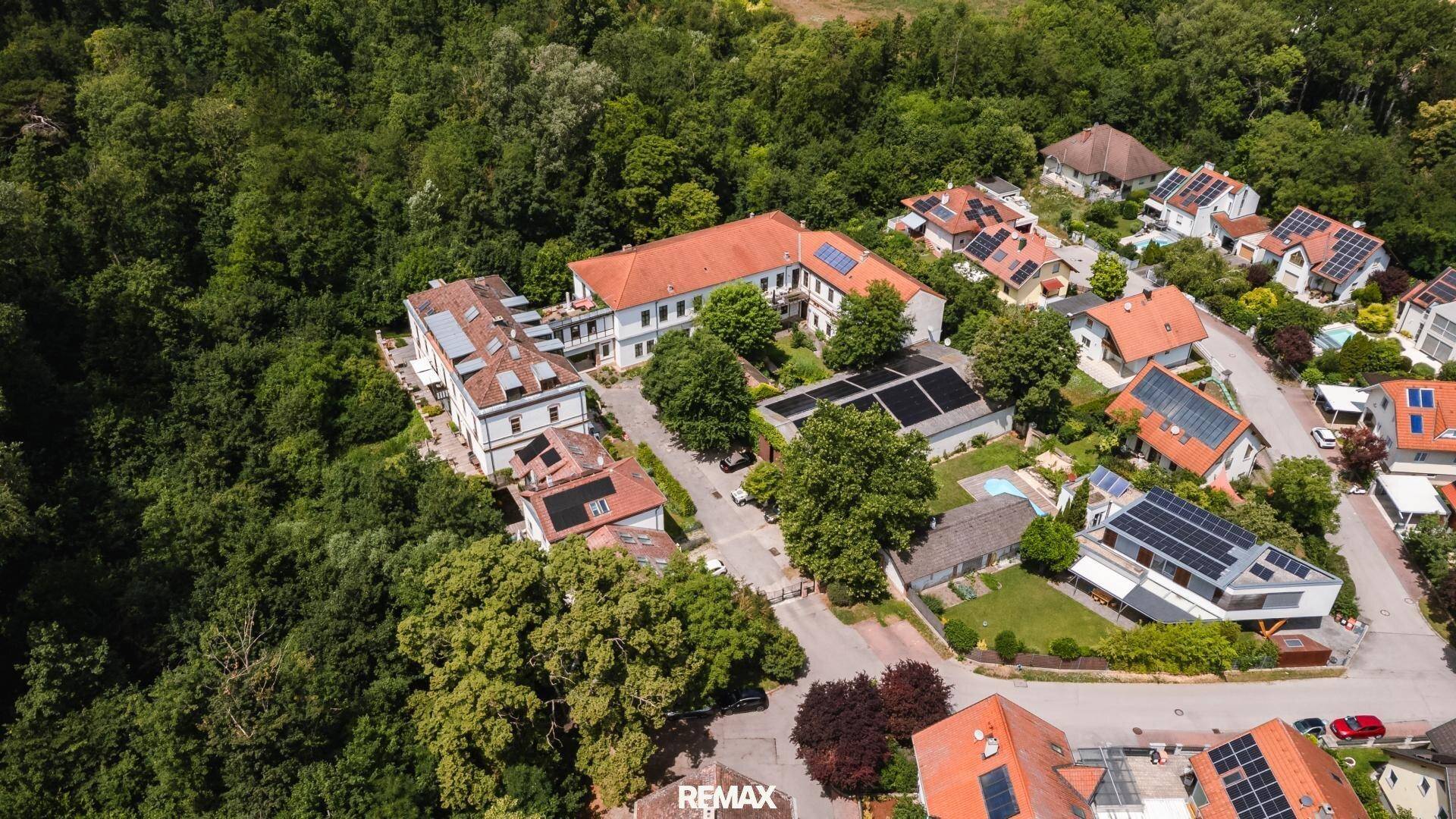 Luftaufnahme des Anwesens mit umliegenden Häusern und viel Grün.