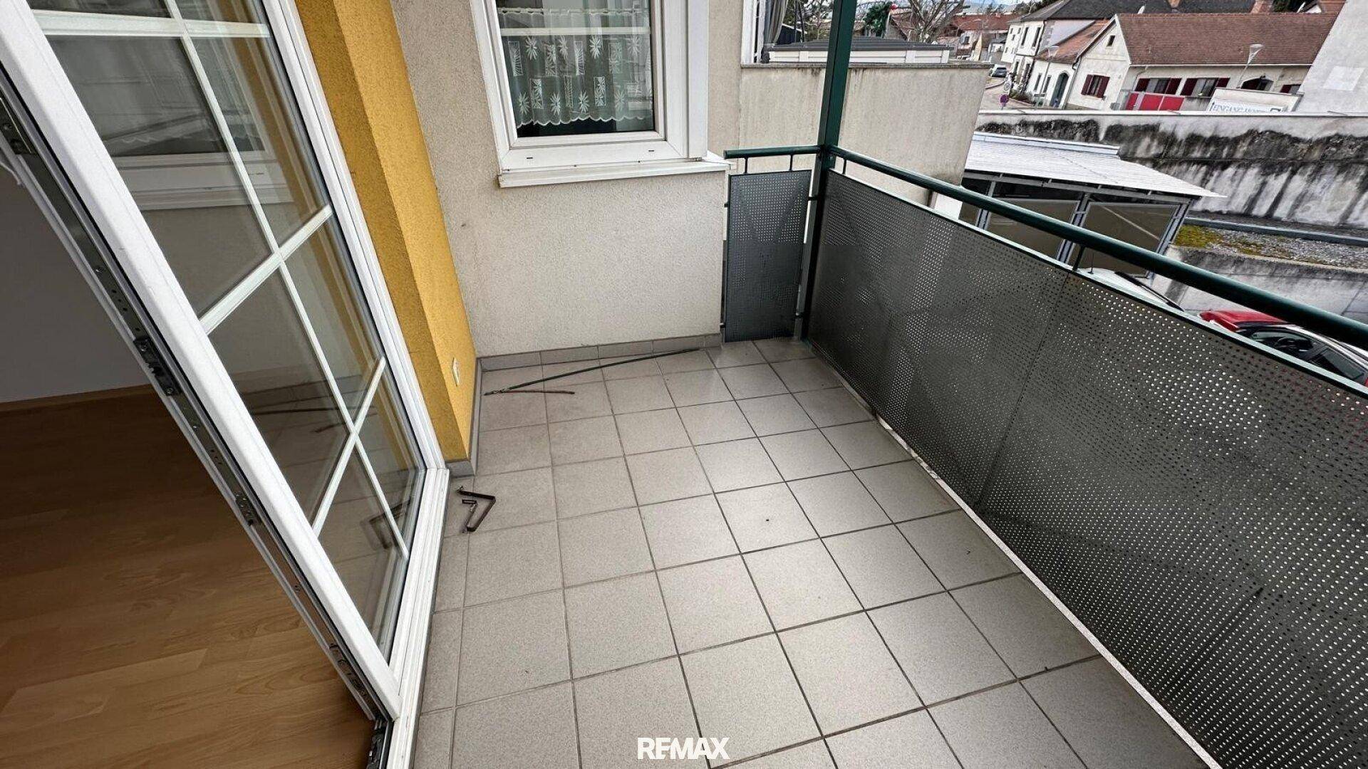 Heller Balkon mit Fliesenboden und Blick auf die umliegende Wohngegend.