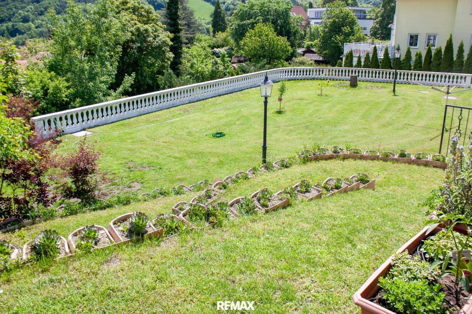 Terrassierter Gartenbereich mit Rasen, Blumenbeeten und einer Balustrade mit Weitblick.