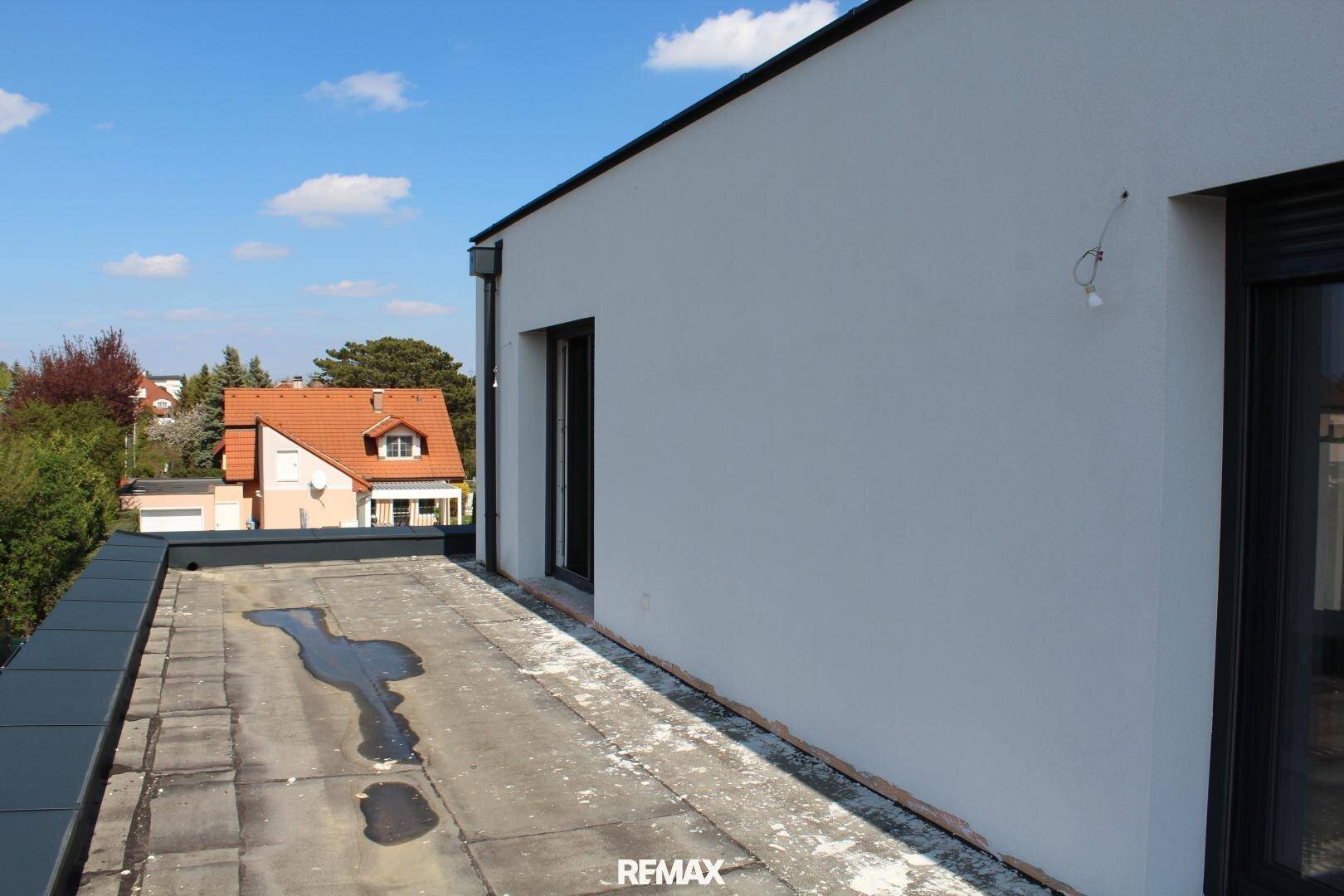 Unfertige Dachterrasse mit Blick auf die umliegenden Häuser und den blauen Himmel.