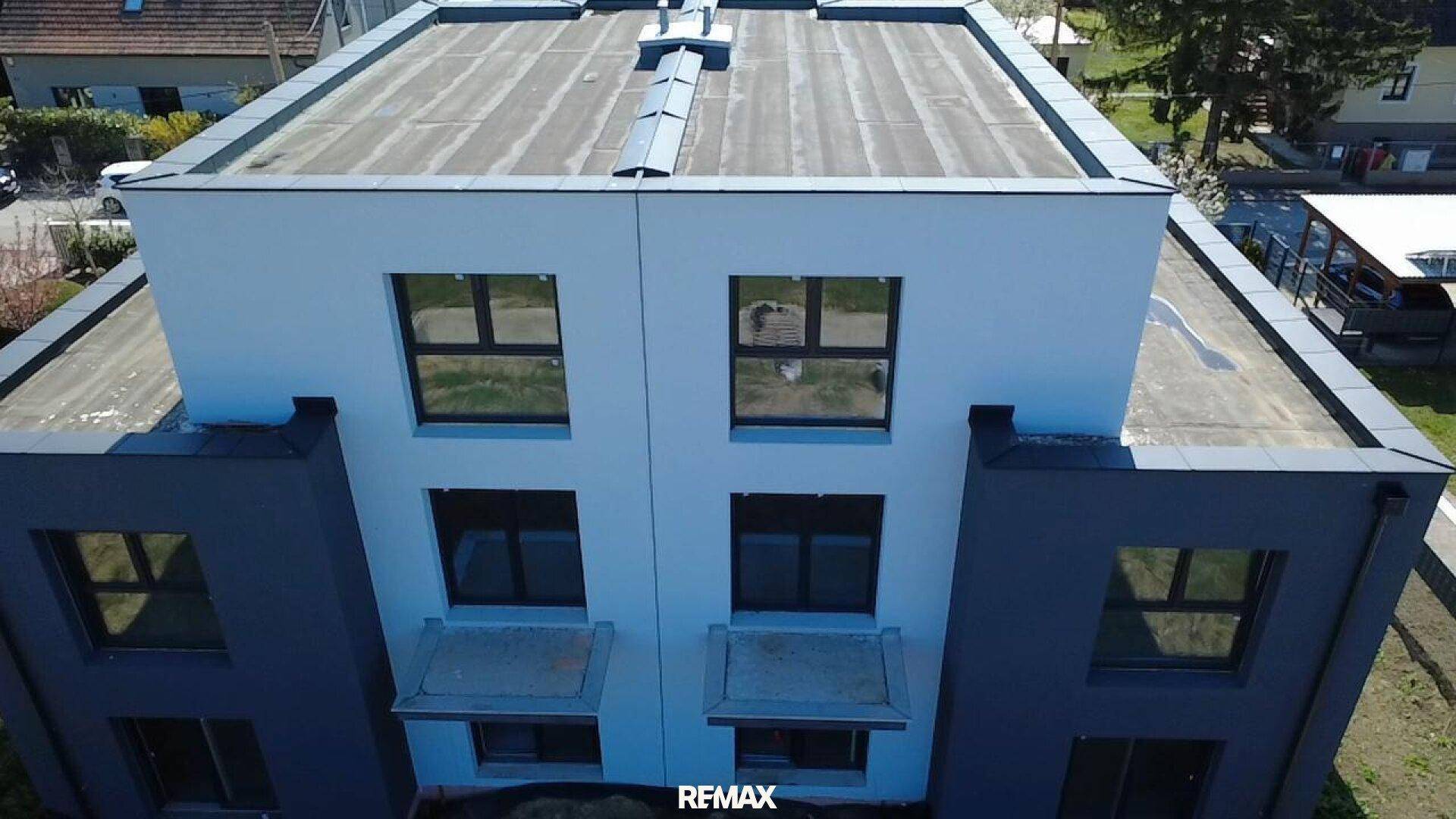 Draufsicht auf das Flachdach eines modernen Gebäudes mit sichtbaren Lüftungselementen.