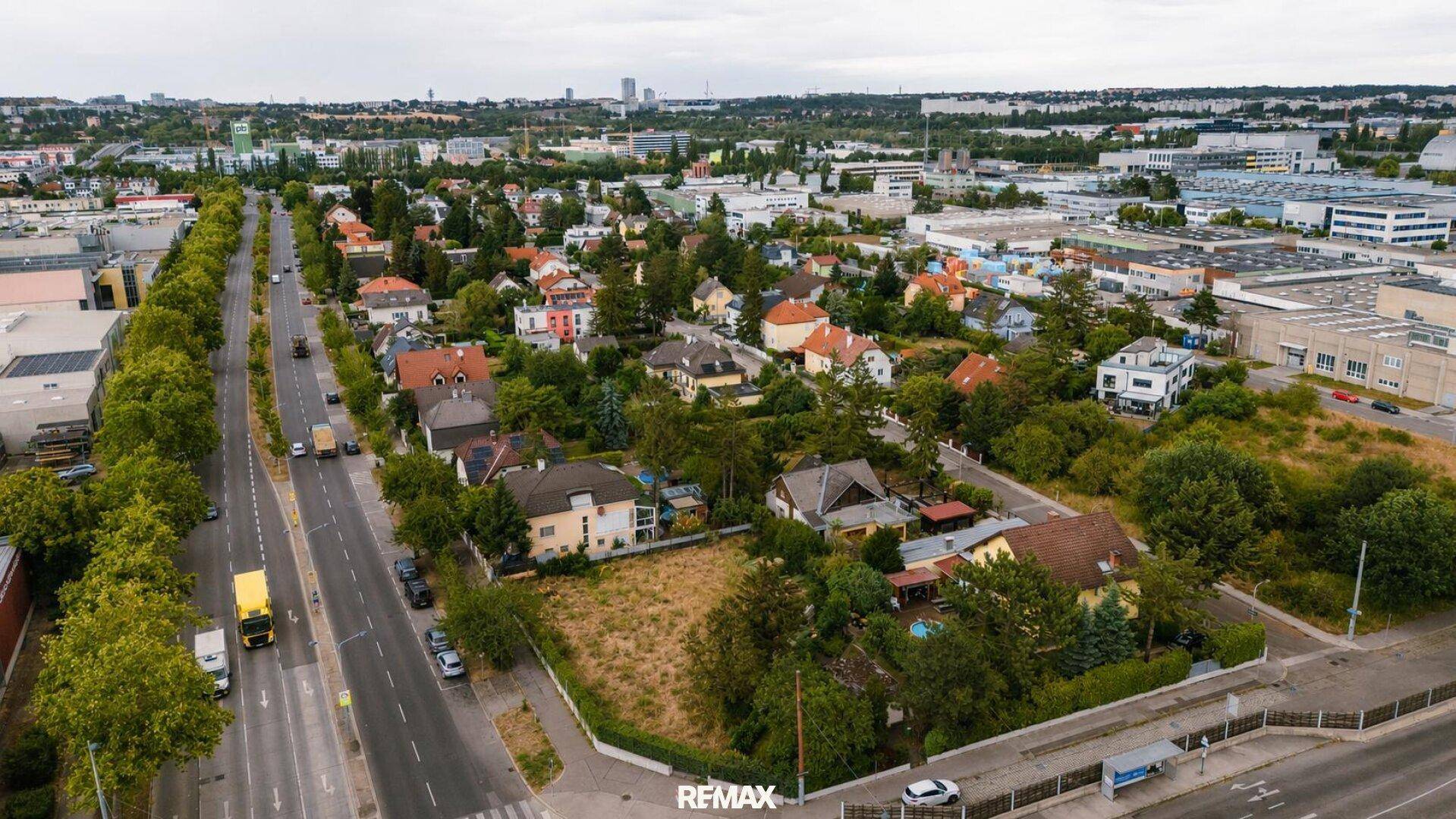 Luftaufnahme einer gemischten Wohn- und Gewerbegegend mit viel Grün und Straßennetz.