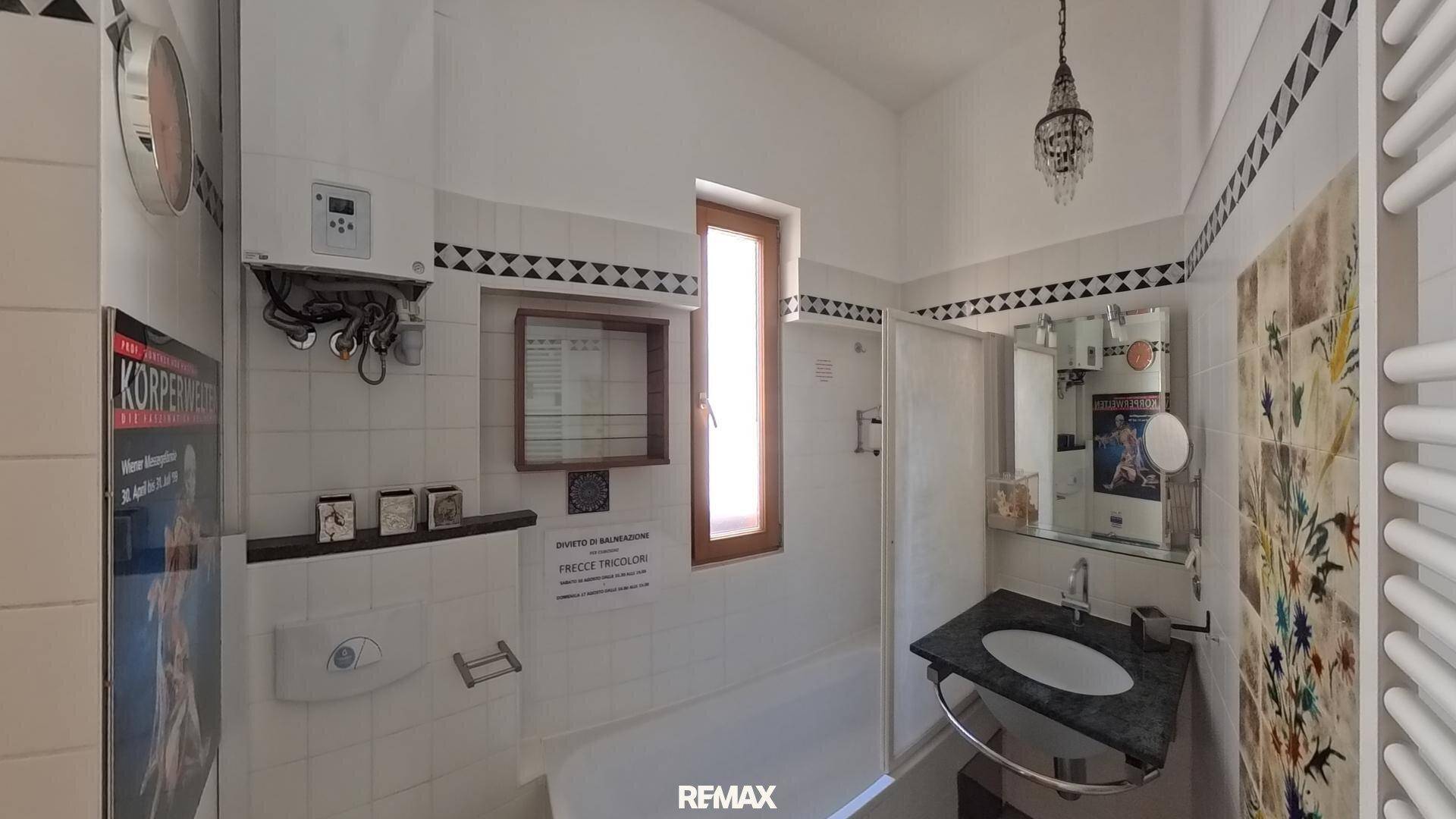 Badezimmer mit Badewanne, Dusche, Fenster und traditionellen Fliesen.